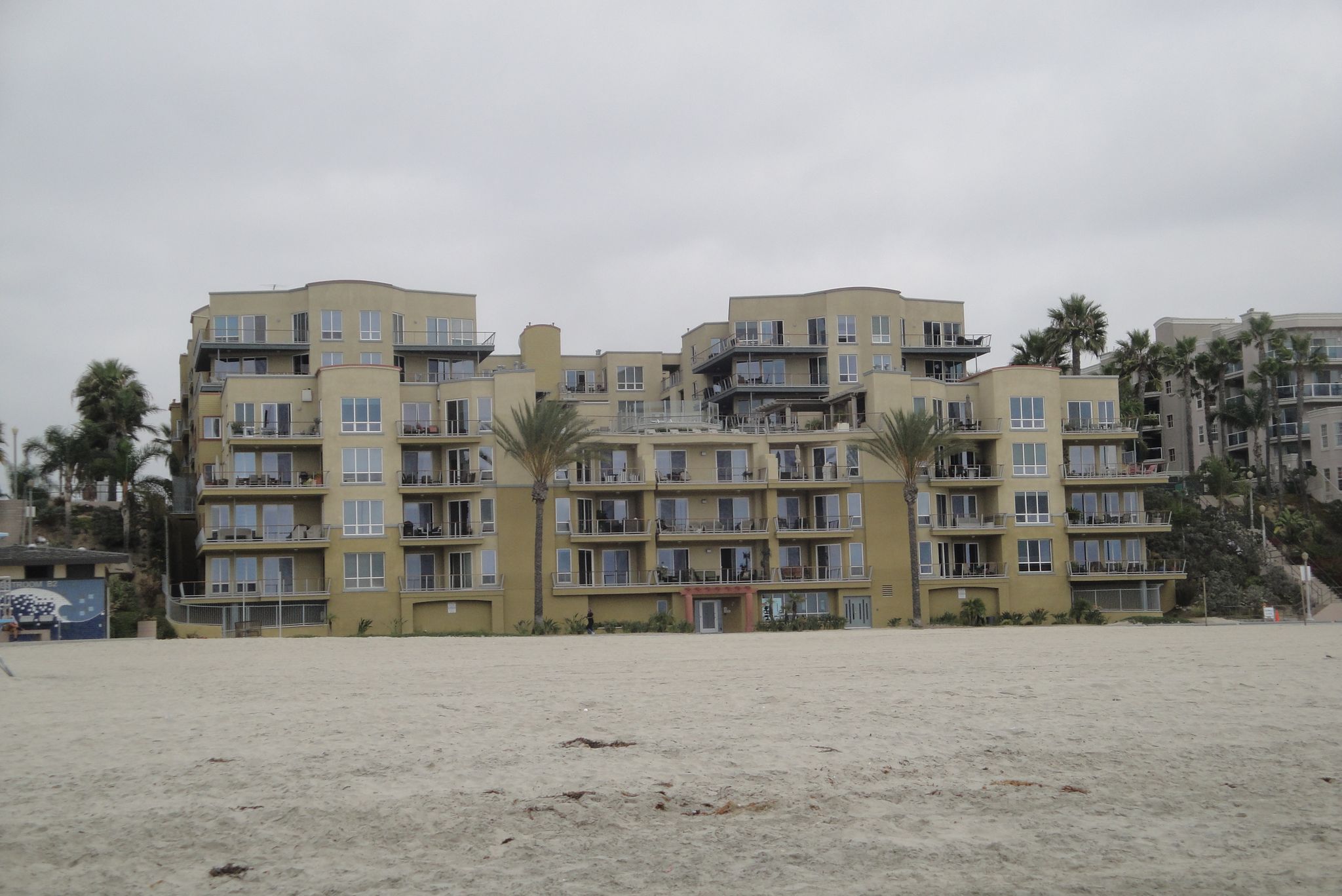 Large yellow apartment buildings with balconies overlooking a wide sandy beach. - Long Beach City Beach – Beautiful Beach Bike Path loop from Naples Islands