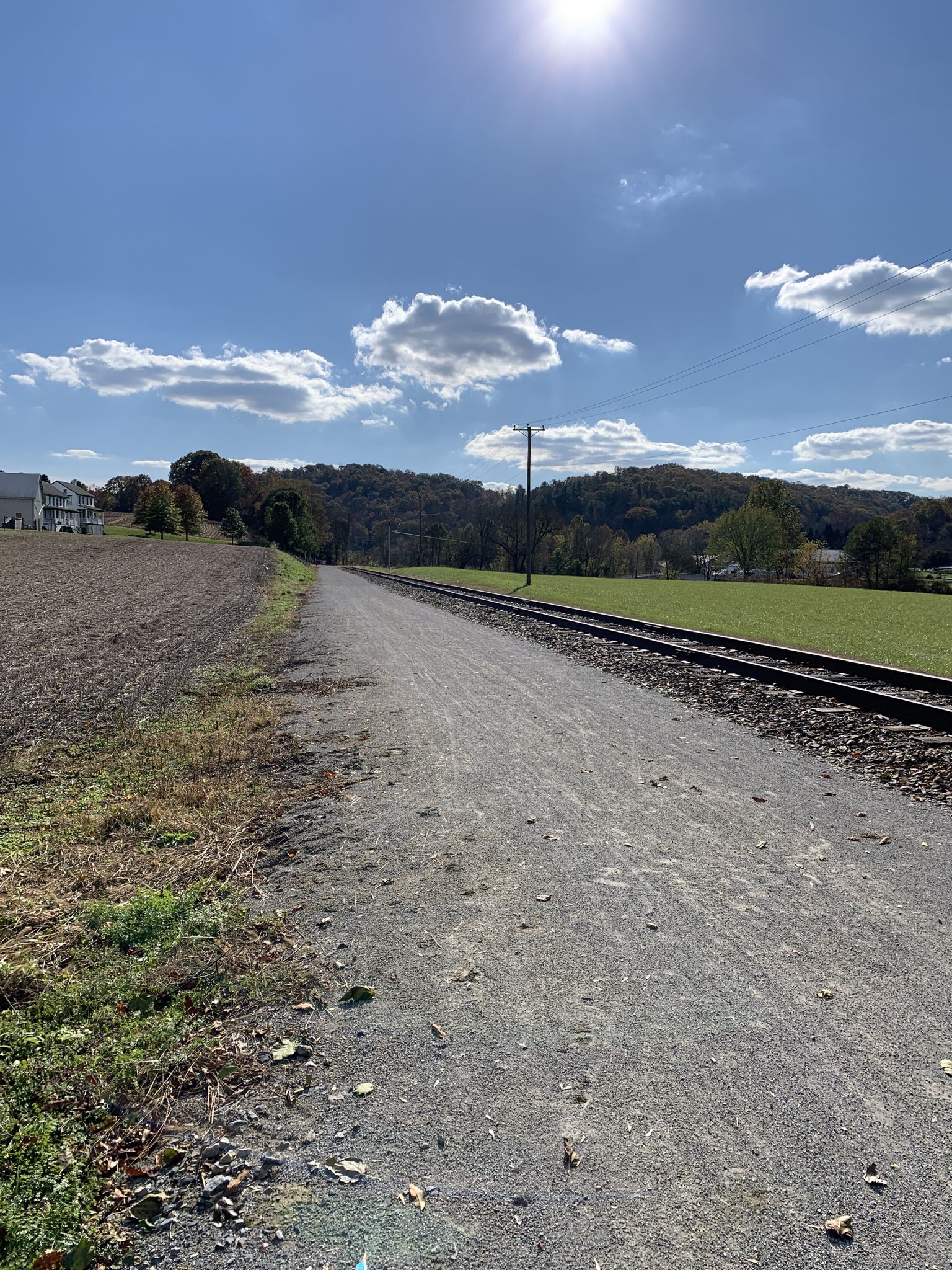 A gravel path and railroad tracks through a rural landscape under a sunny sky. - New Freedom Rail Trail – New Freedom loop from New Freedom