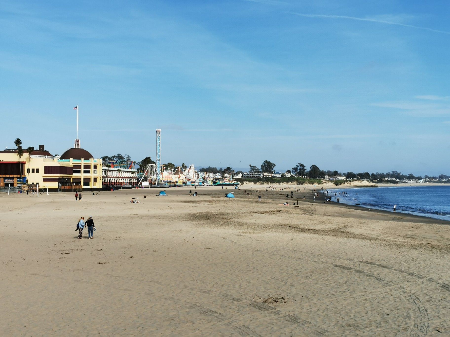Wide sandy beach with distant amusement park buildings and people walking. - Santa Cruz Wharf Walk
