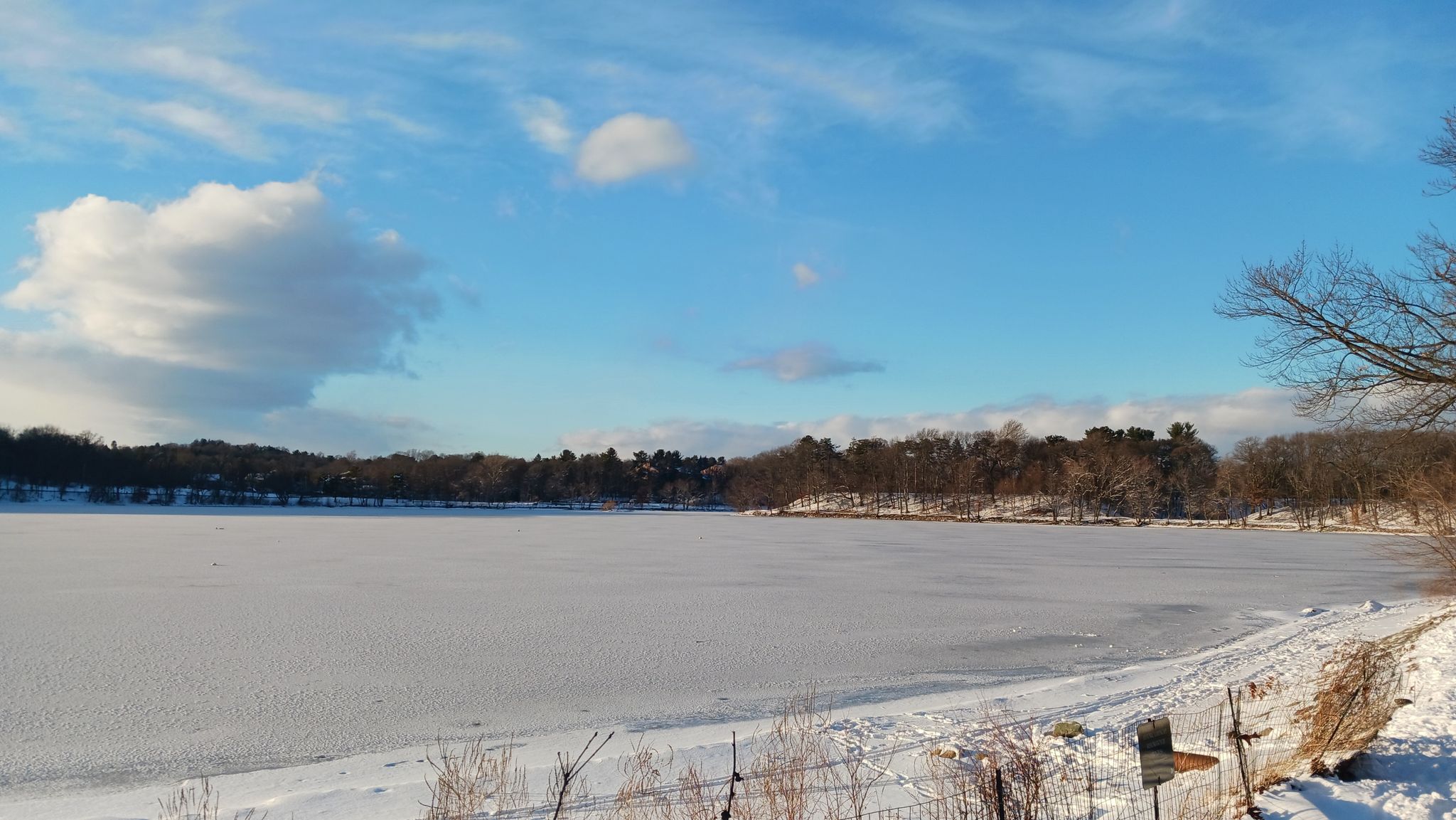 A vast frozen lake covered in snow, with distant trees under a blue sky. - Walking City Trail: Section 3