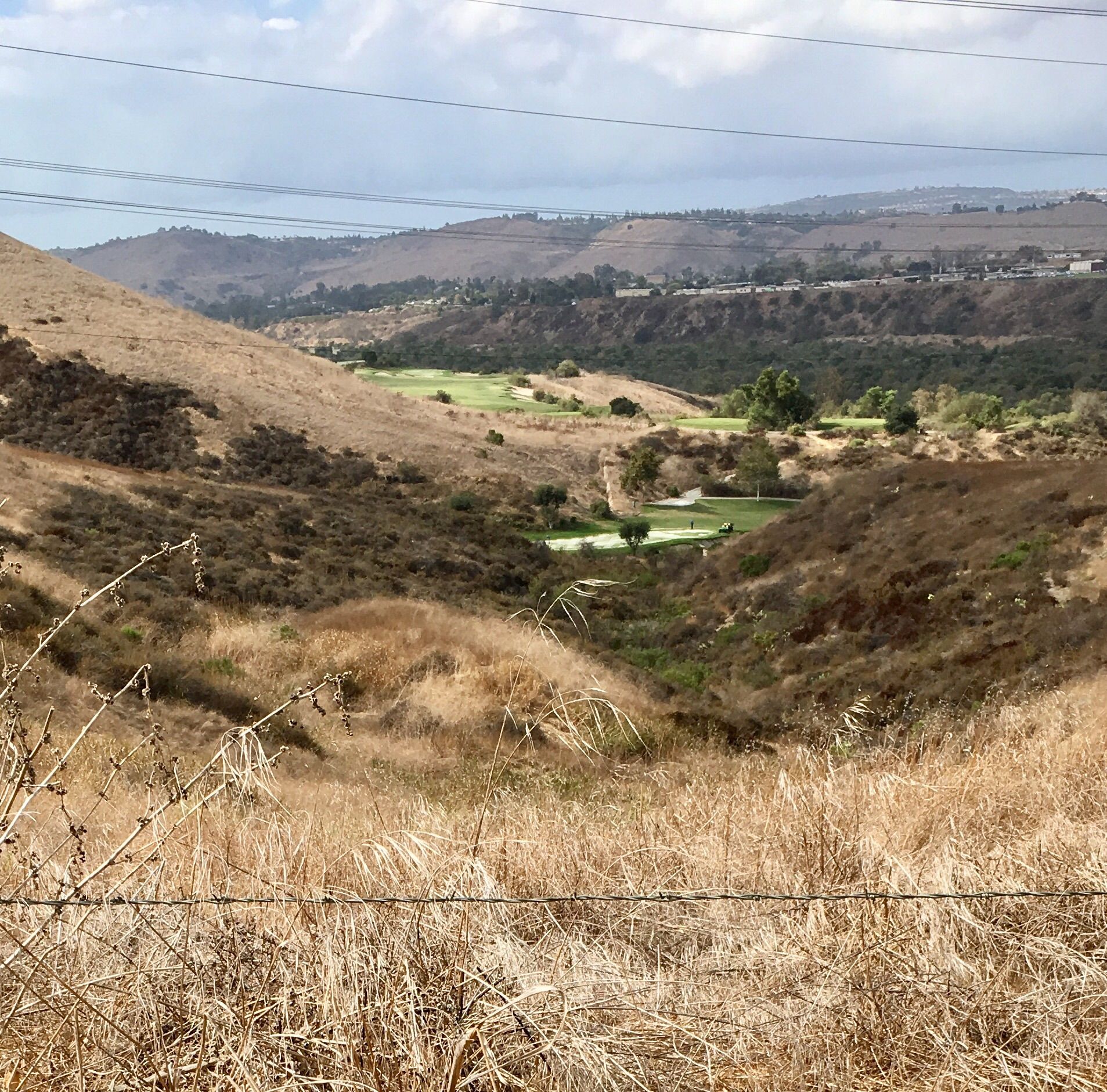 Dry, grassy hills overlooking a green golf course in a valley. - San Juan Creek and Ladera Ranch Loop