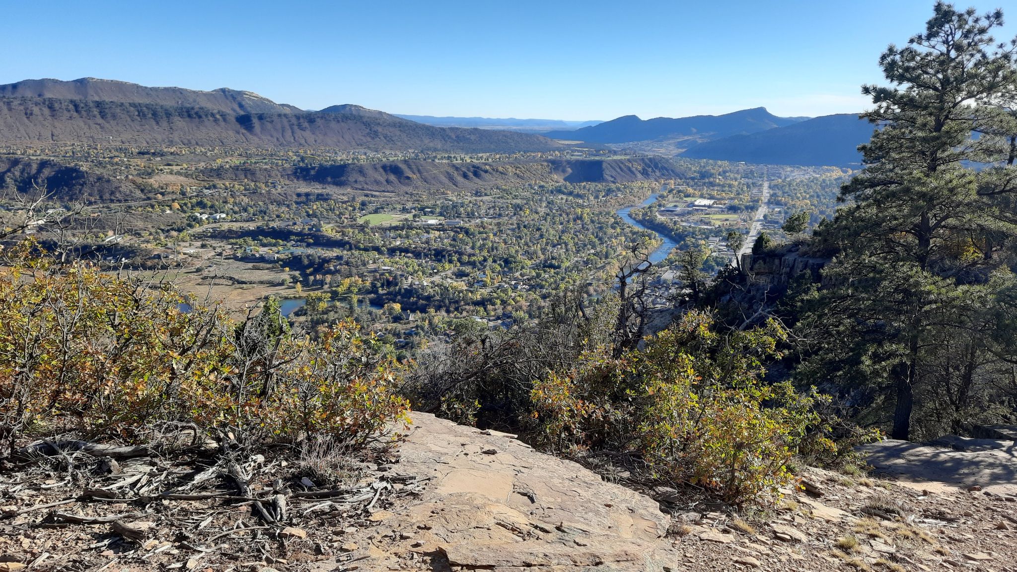 Panoramic view of a valley with a winding river and distant town. - Animas Mountain Loop