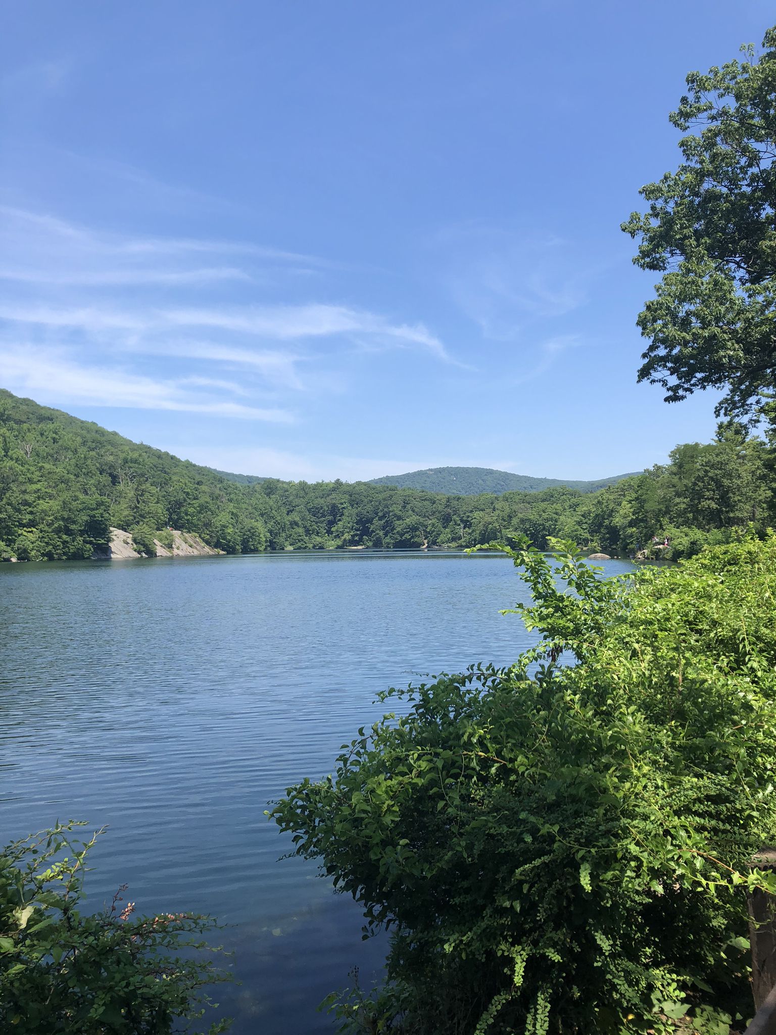 Calm lake surrounded by lush green mountains under a bright blue sky. - Hessian Lake Loop