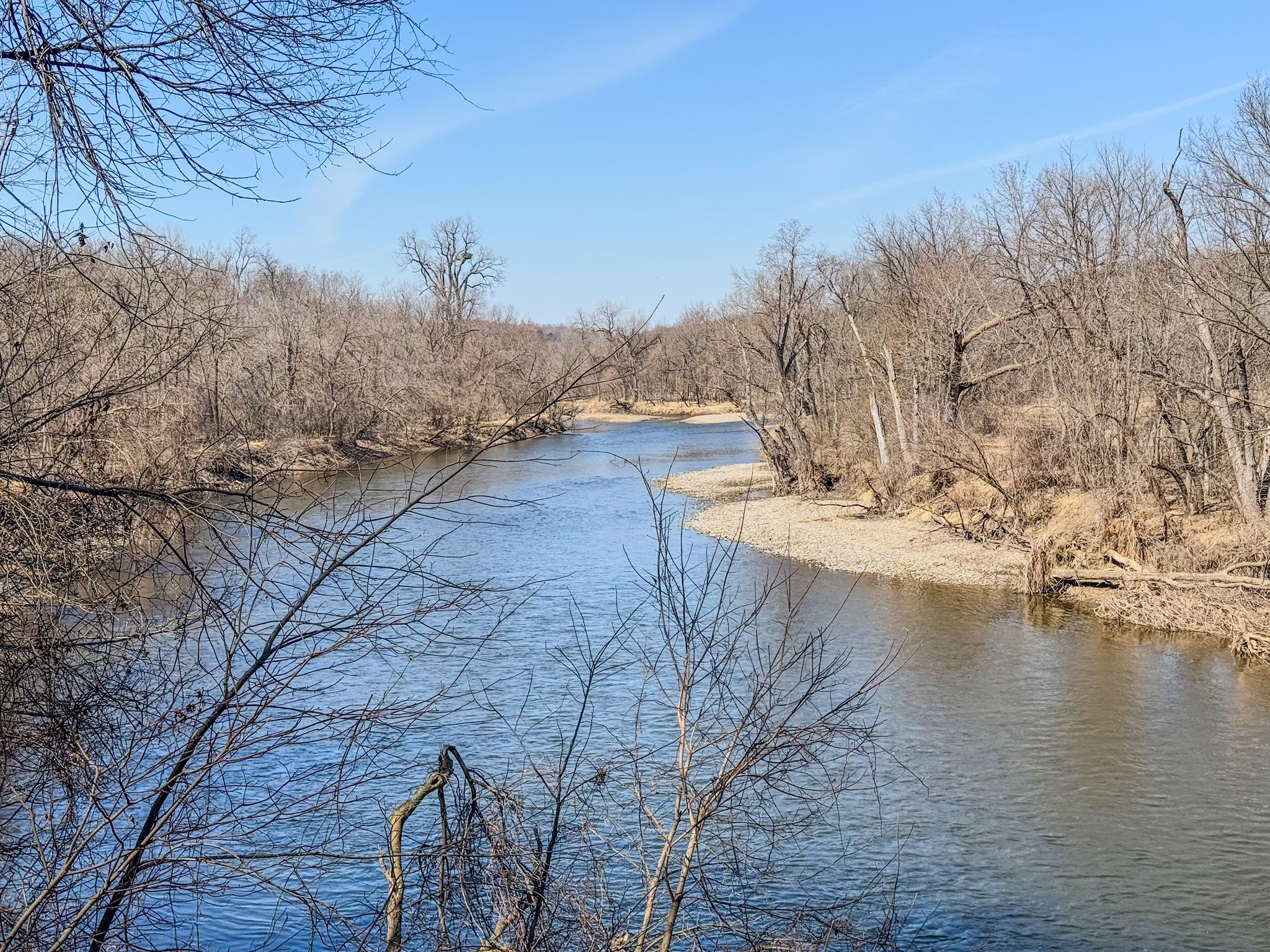 A river winds through bare trees under a clear blue sky. - One Lane Bridge – Cannon Valley Trail loop from Cannon Falls