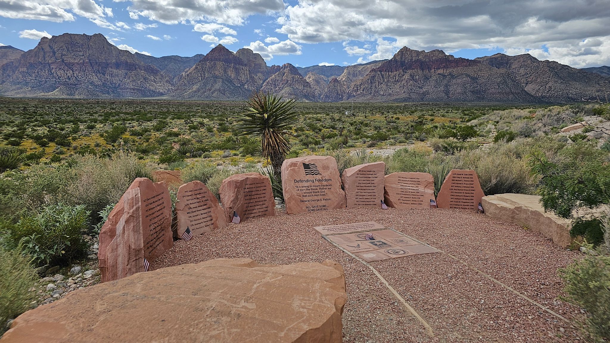 Stone interpretive display in a desert landscape with distant mountains under cloudy sky. - Moenkopi Ridge and Calico Hills Loop