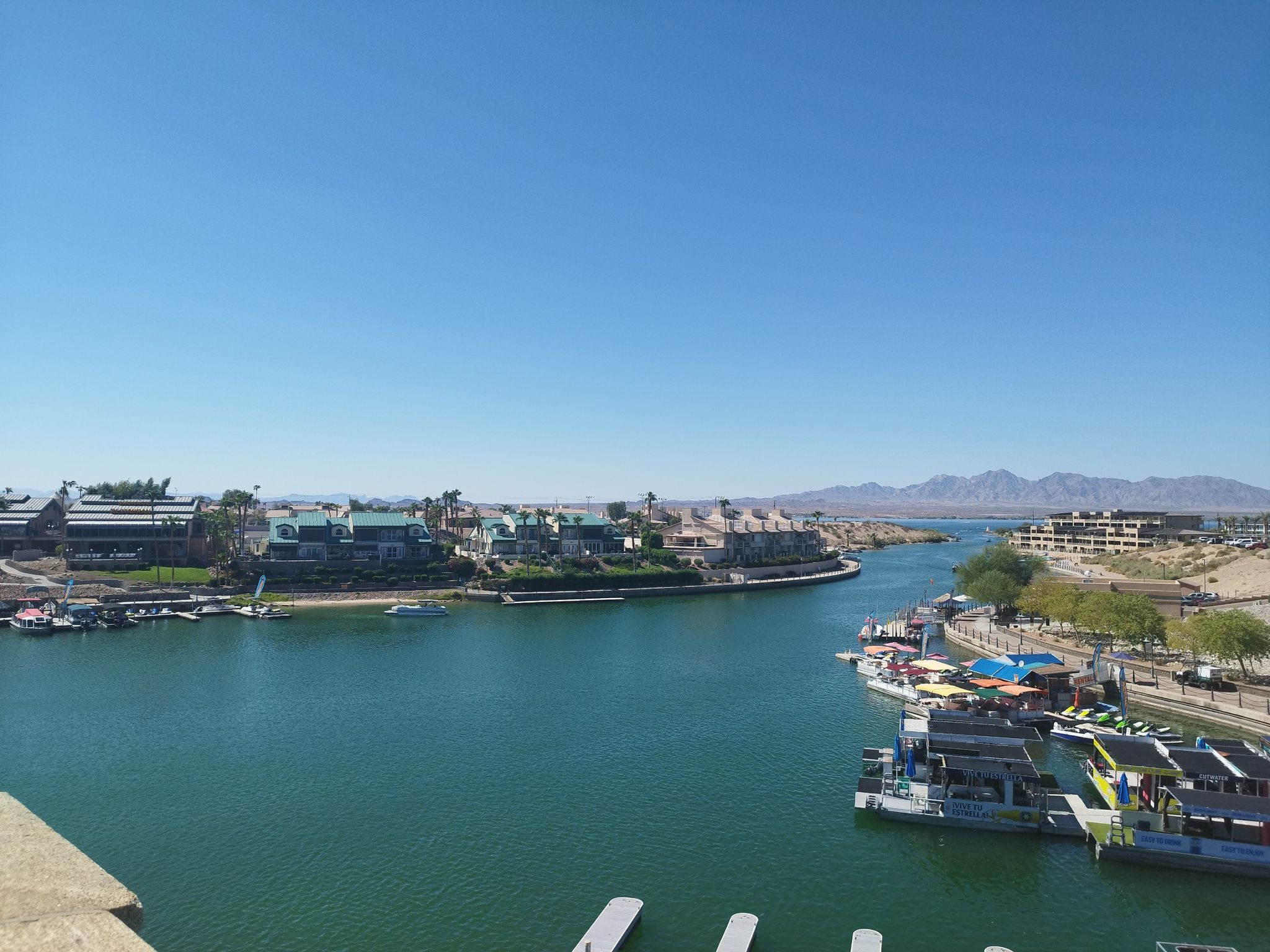 Wide view of a waterway with buildings and boats under a clear blue sky. - Lake Havasu City loop