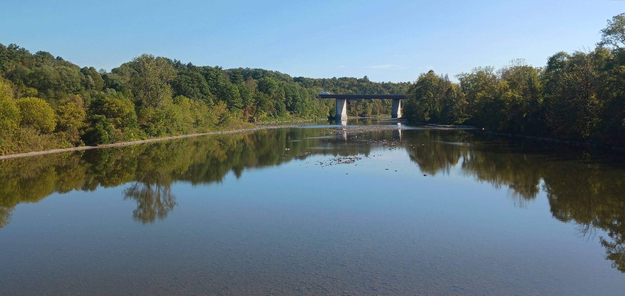 Calm river reflecting trees and a distant bridge under a clear sky. - Highwheeler Coffee – Red Brick Church loop from Ephratah