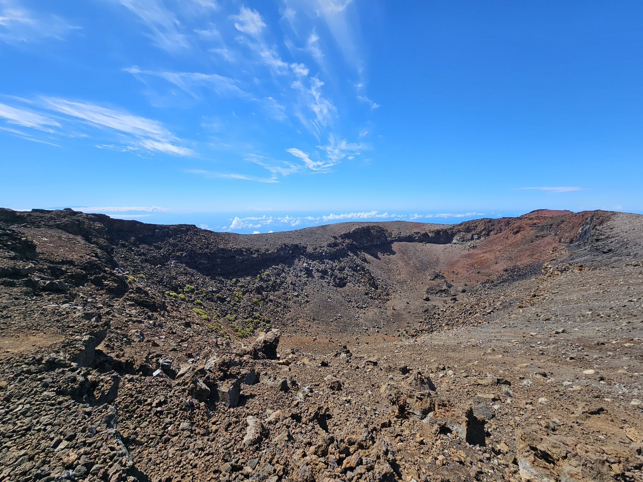 A vast, barren volcanic crater with rocky walls under a blue sky. - Skyline Trail