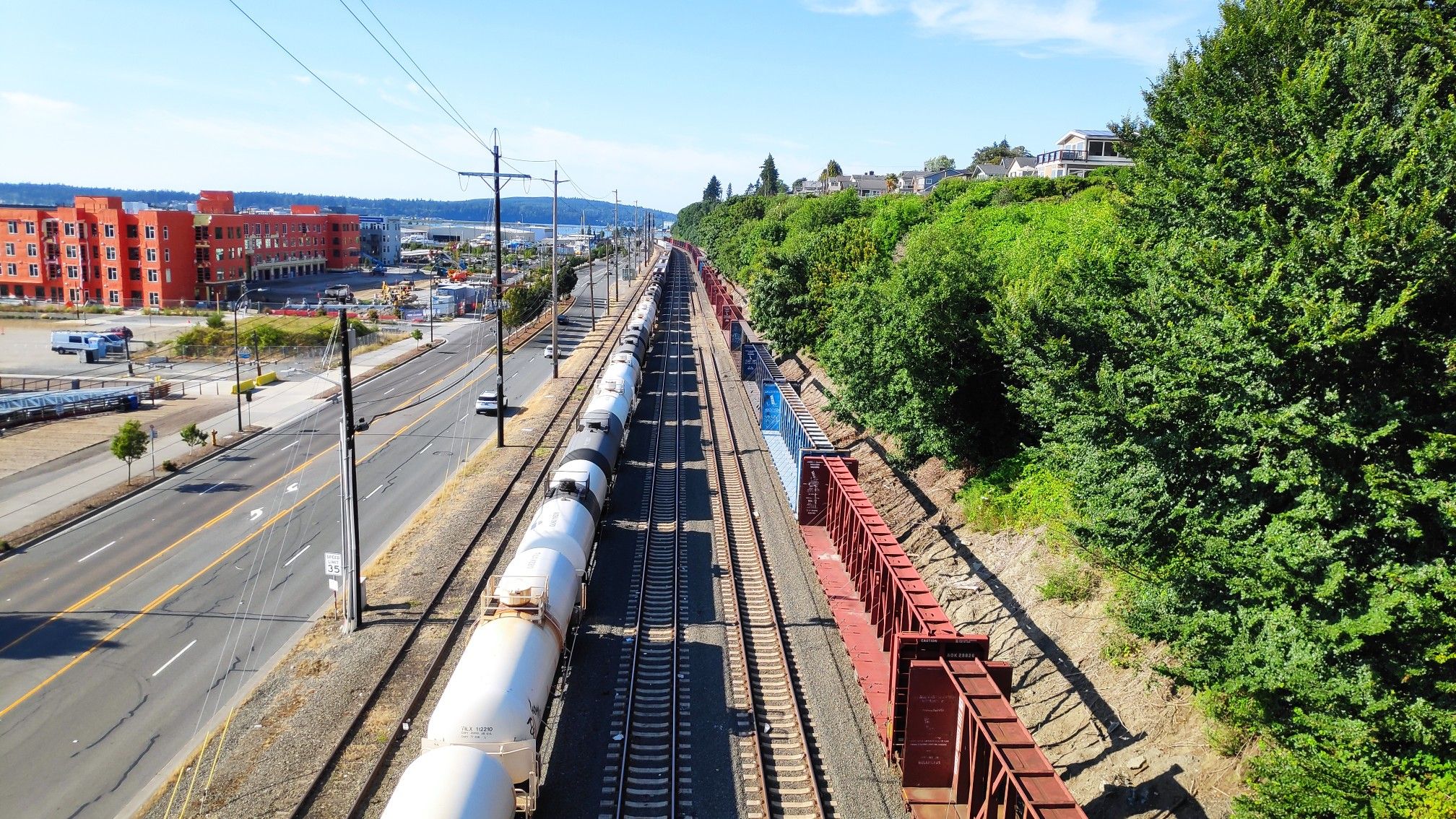 Aerial view of train tracks, freight cars, road, and buildings on a sunny day. - Hiking loop from Everett
