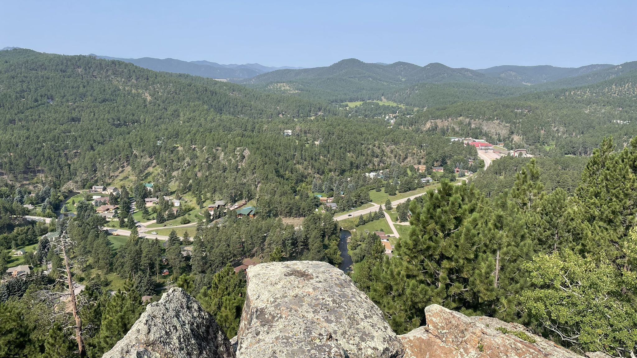 Panoramic view of a green valley with a town and distant mountains under clear sky. - Bone Collector and Bone Up Loop