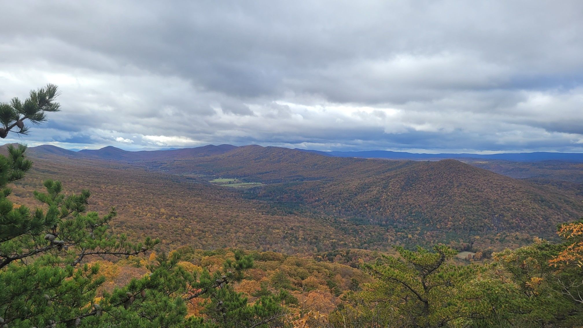 Vast autumn mountain landscape under a cloudy sky, with a valley below. - Halfmoon Mountain Loop