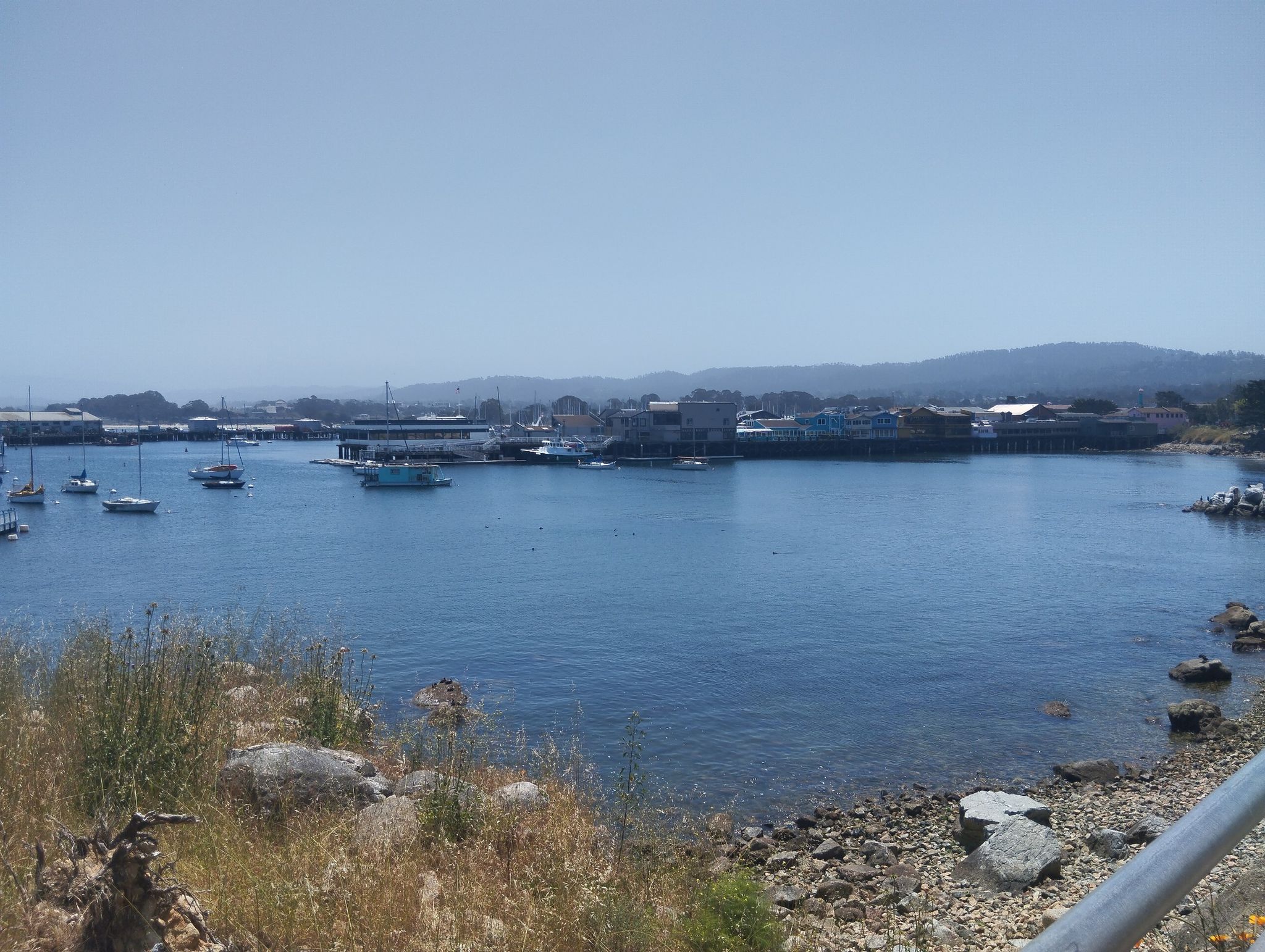 Calm blue harbor filled with boats, distant buildings, and hills. - Cannery Row – Cannery Row, Monterey loop from Monterey