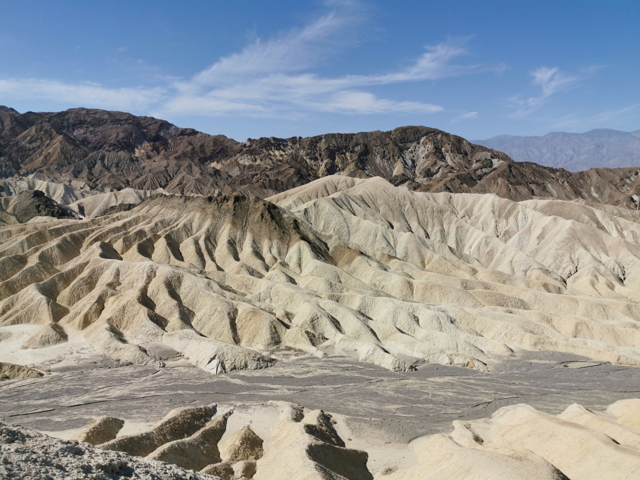 Eroded desert badlands with light-colored hills and dark mountains under a clear sky. - Golden Canyon, Gower Gulch and Badlands Loop