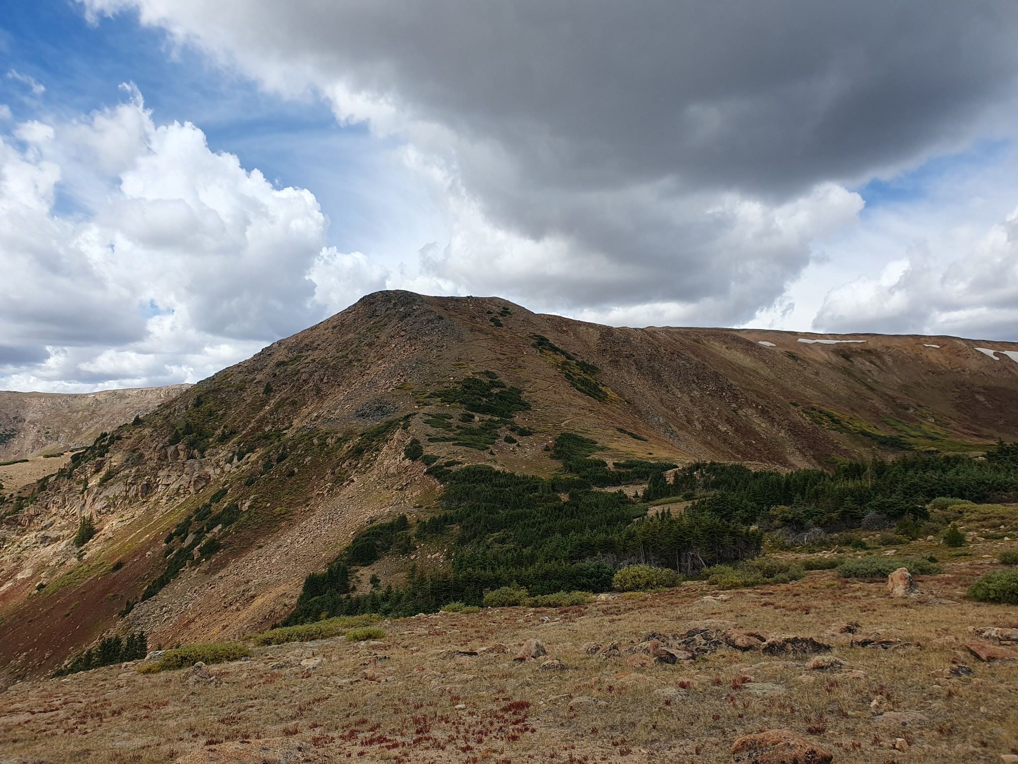 Barren mountain slope with patches of green under a dramatic cloudy sky. - Stanley Mountain from Berthoud Pass