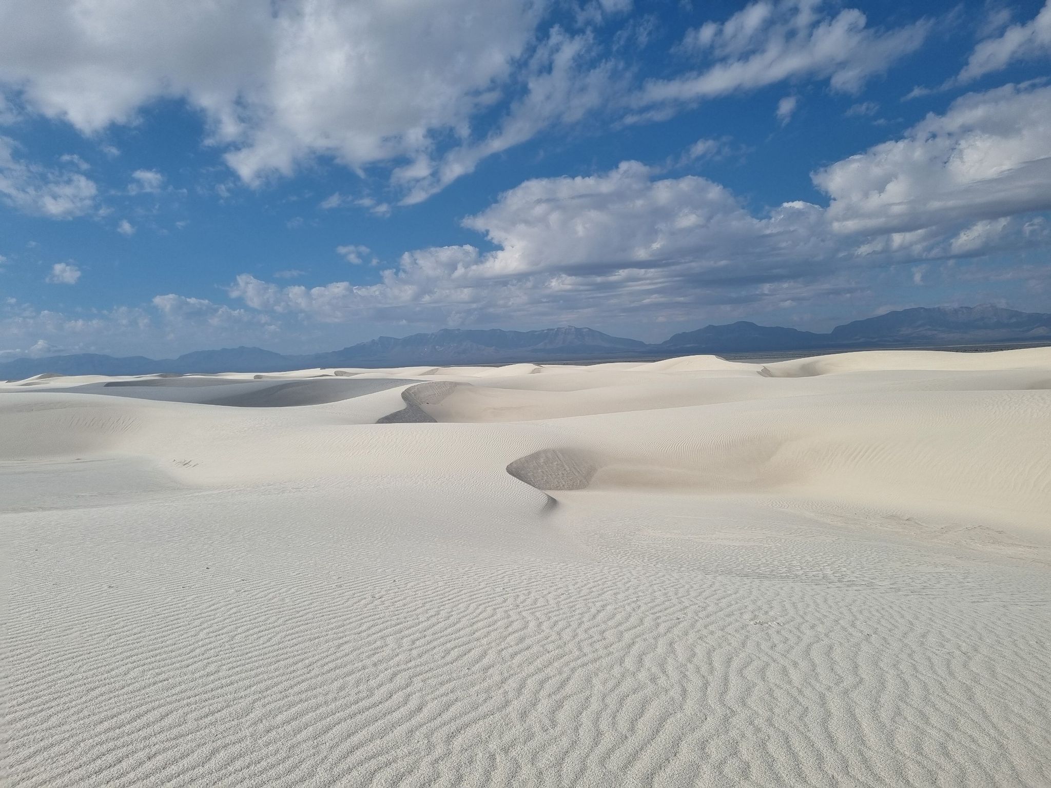 Rippled white sand dunes stretch under a partly cloudy blue sky. - Alkali Flat Trail