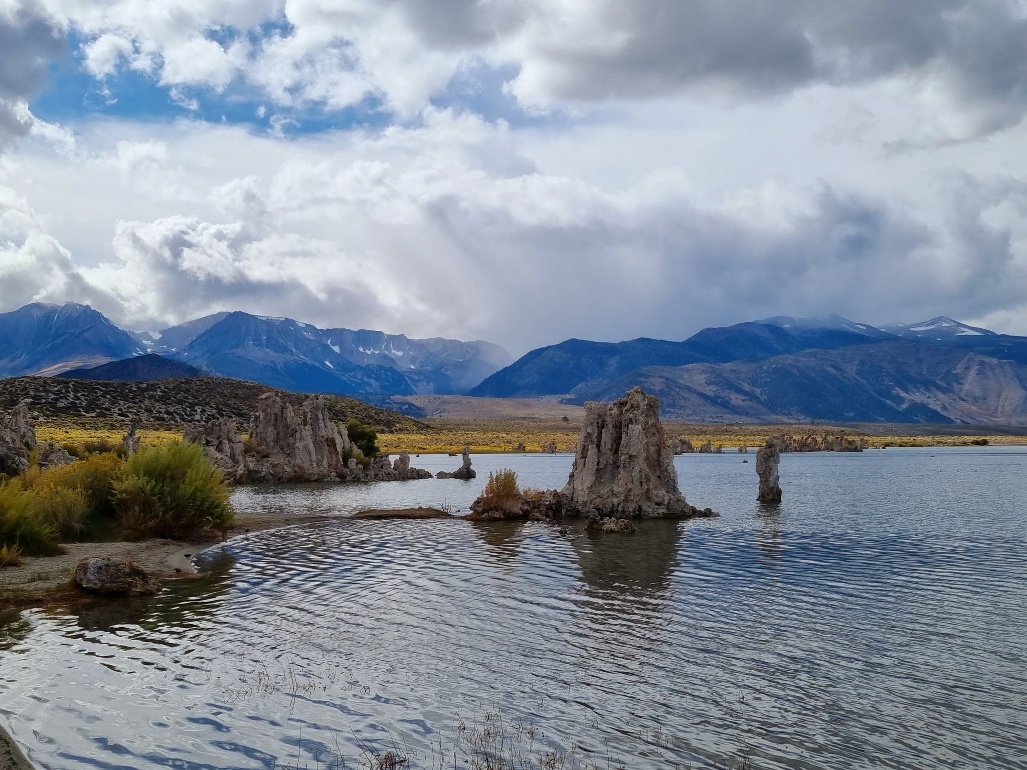 Lake with tufa formations, distant mountains, and cloudy sky. - South Tufa Loop Trail