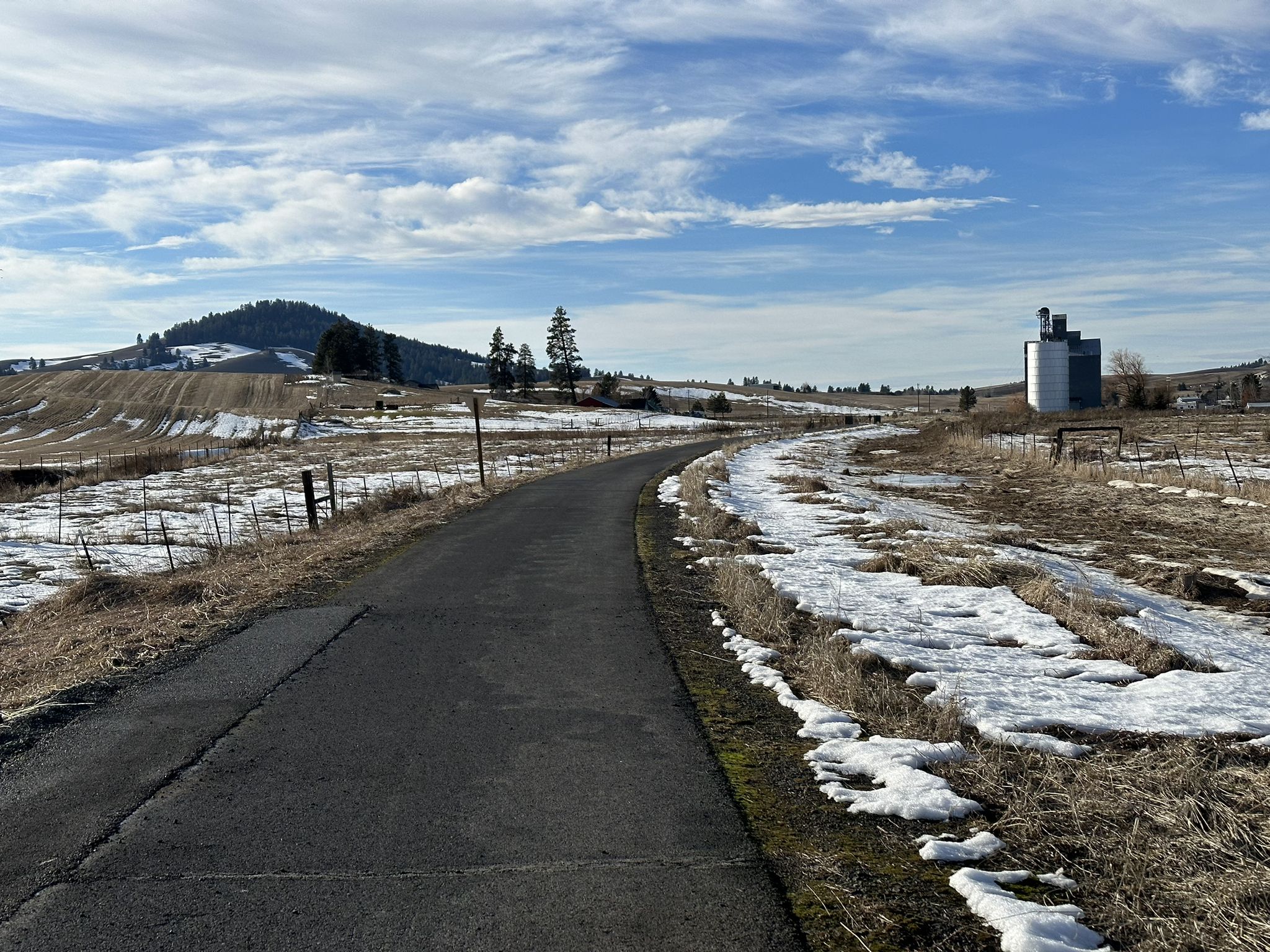 Paved road through snowy, dry fields with a distant hill under a cloudy sky. - Paradise Path – Stone Wall Bench loop from Moscow