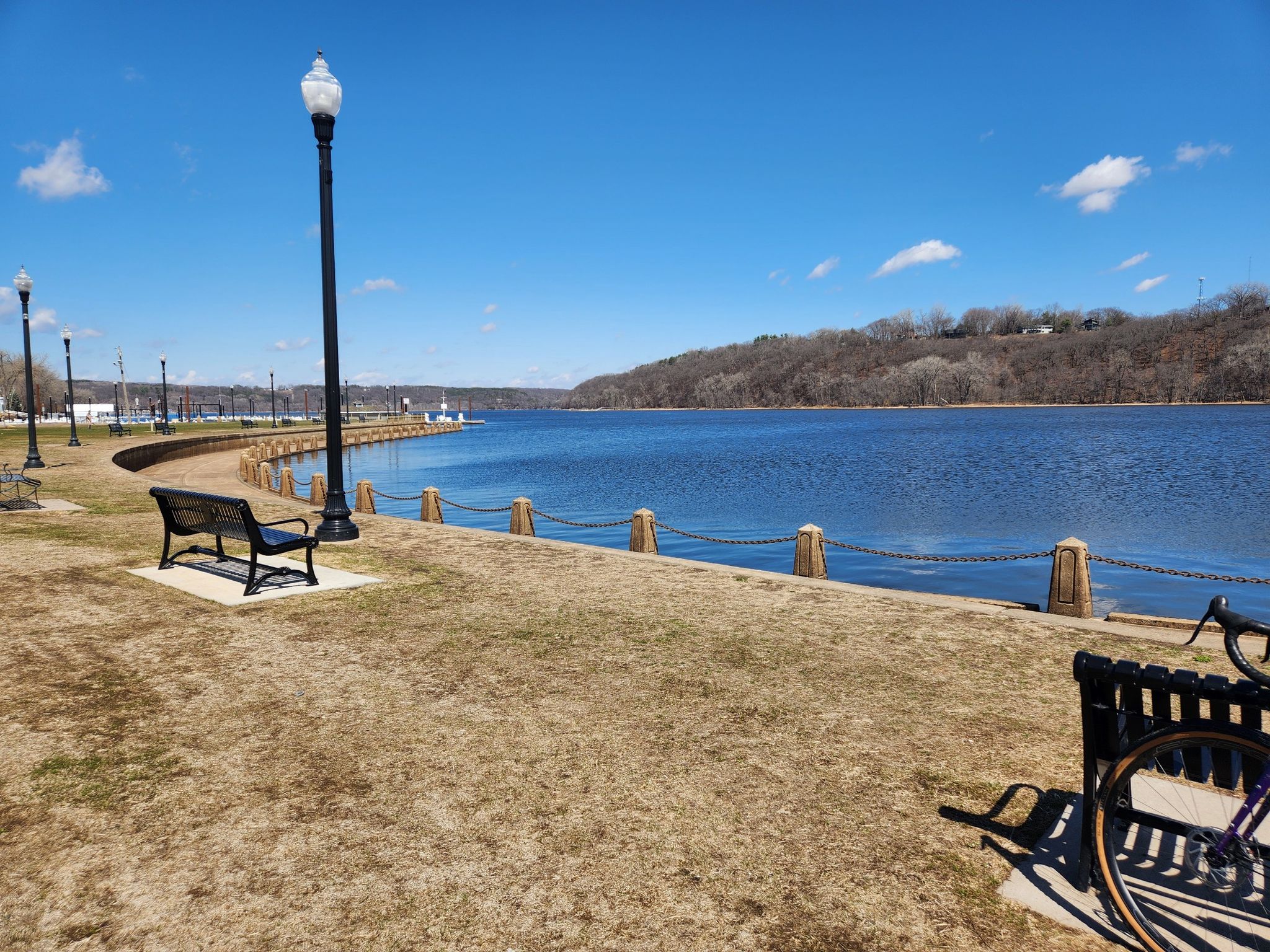A sunny waterfront park with benches and lampposts beside a wide river. - Scenic overlook – Lake McKusick loop from Stillwater