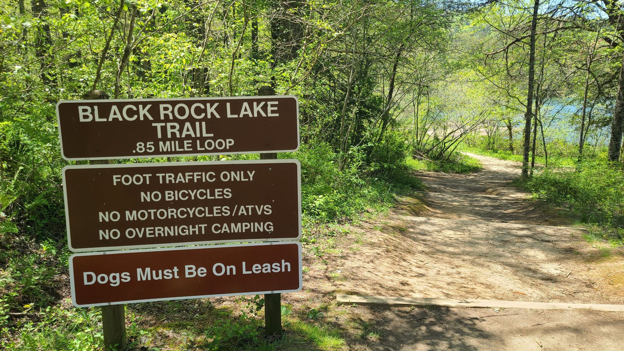 Brown trail sign with rules next to a dirt path leading into a green forest. - Black Rock Lake loop from Little Tennessee Bartram Trail Project