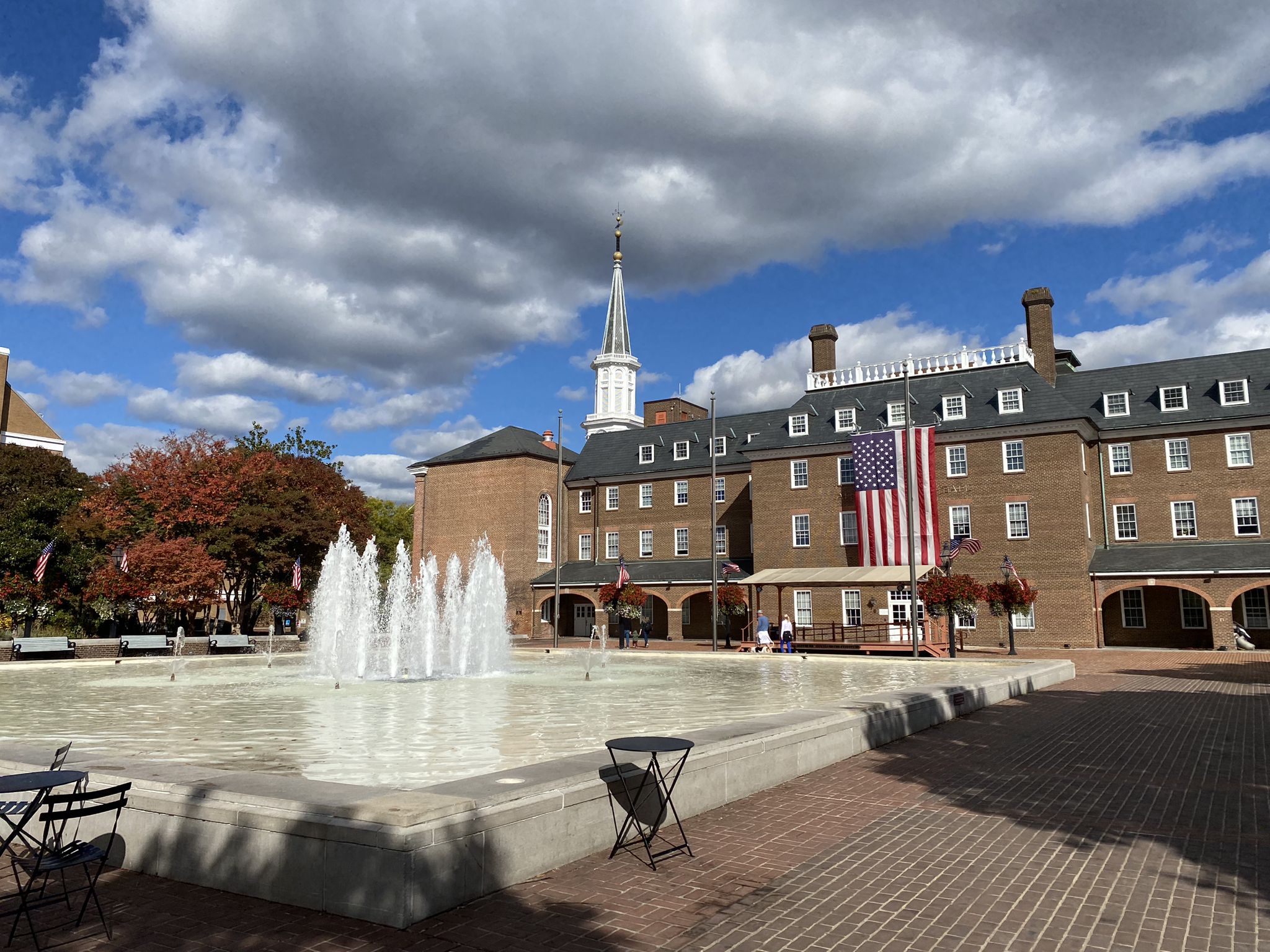 Large fountain in a plaza with a brick building, blue sky. - Alexandria City Marina – Waterfront Park loop from Van Dorn Street
