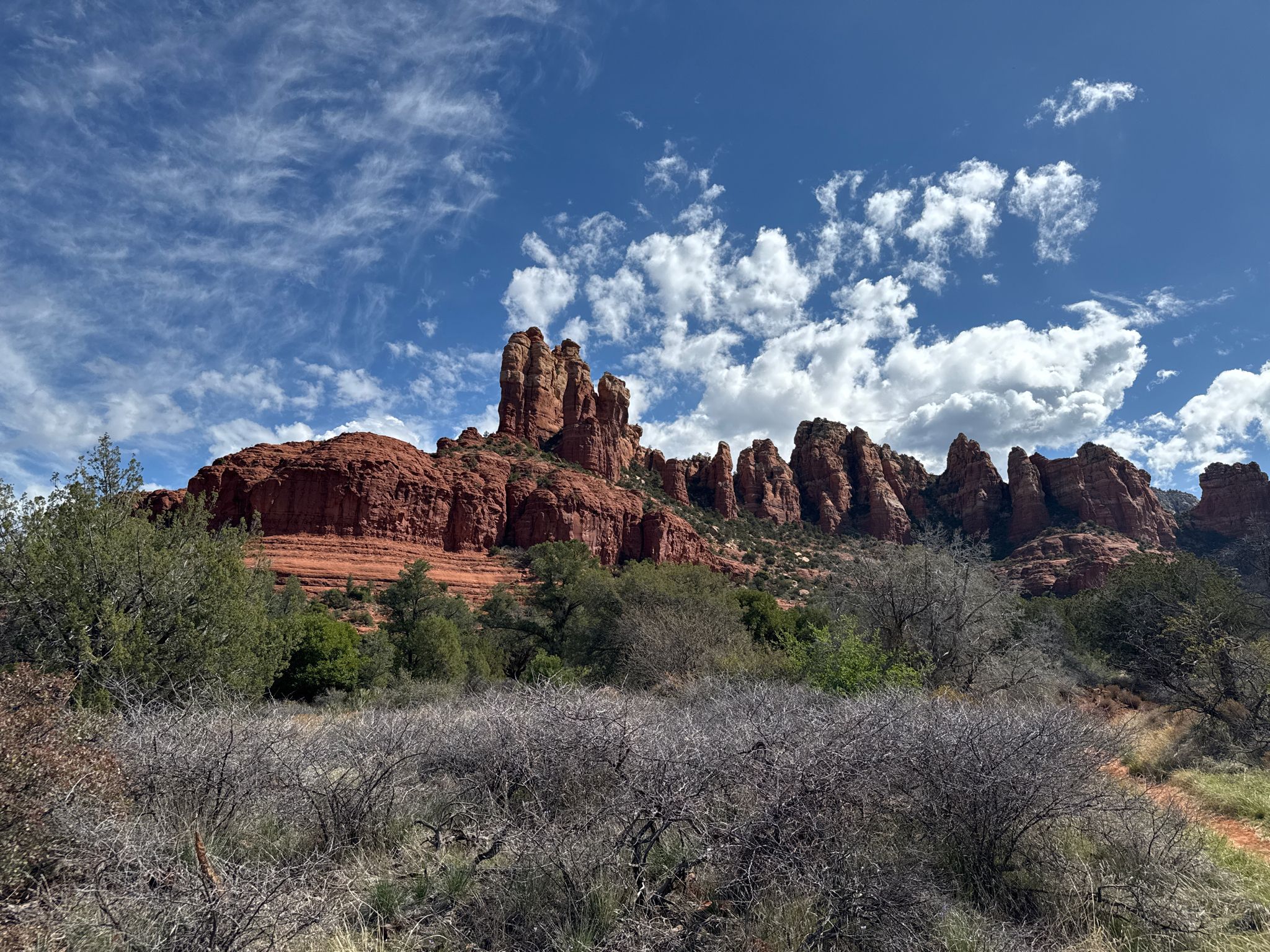 Red rock formations and desert shrubs under a partly cloudy blue sky. - Margs Draw Spur A Trail