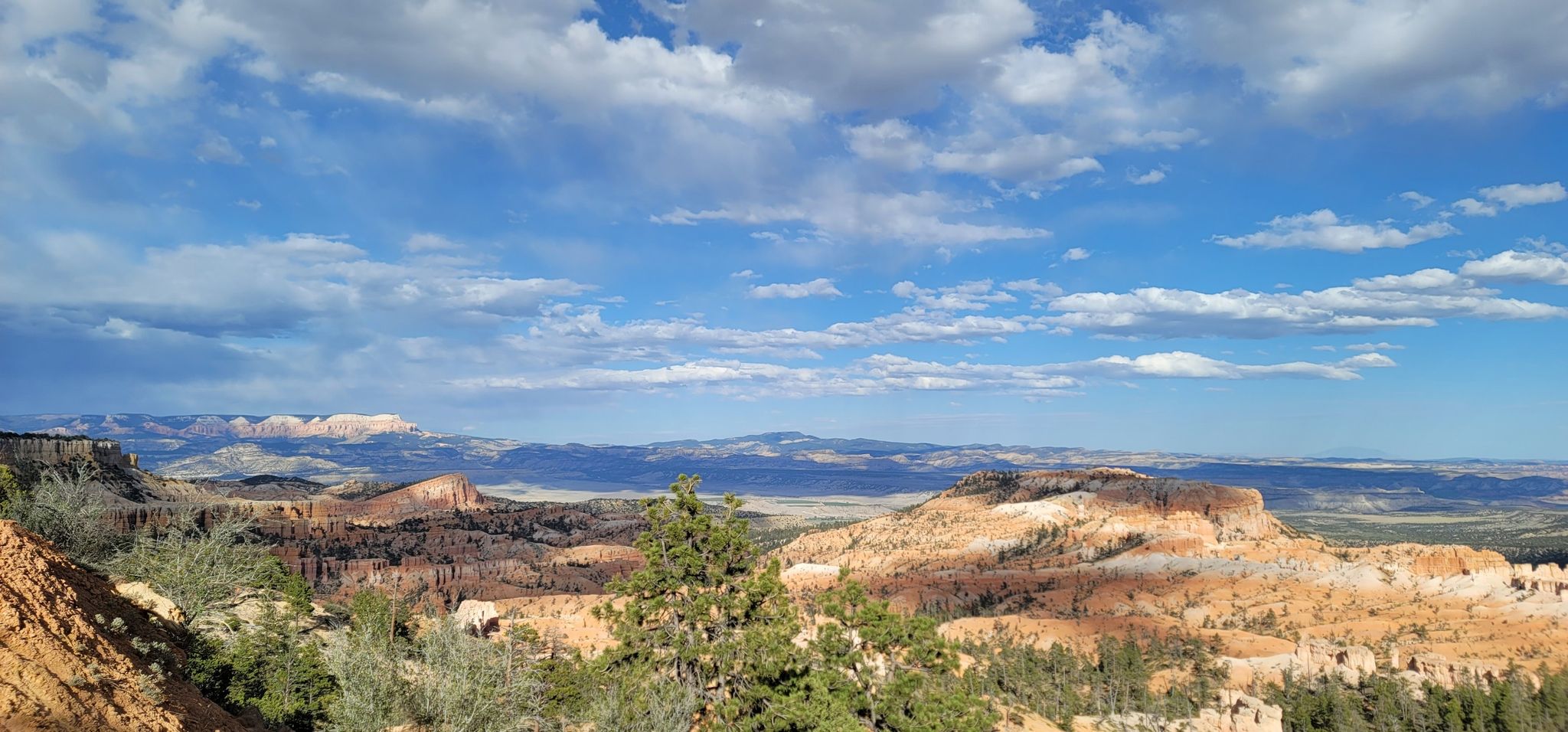 Vast desert landscape with distant mountains and rock formations under a blue sky. - Sunrise Point loop from Bryce Canyon Lodge