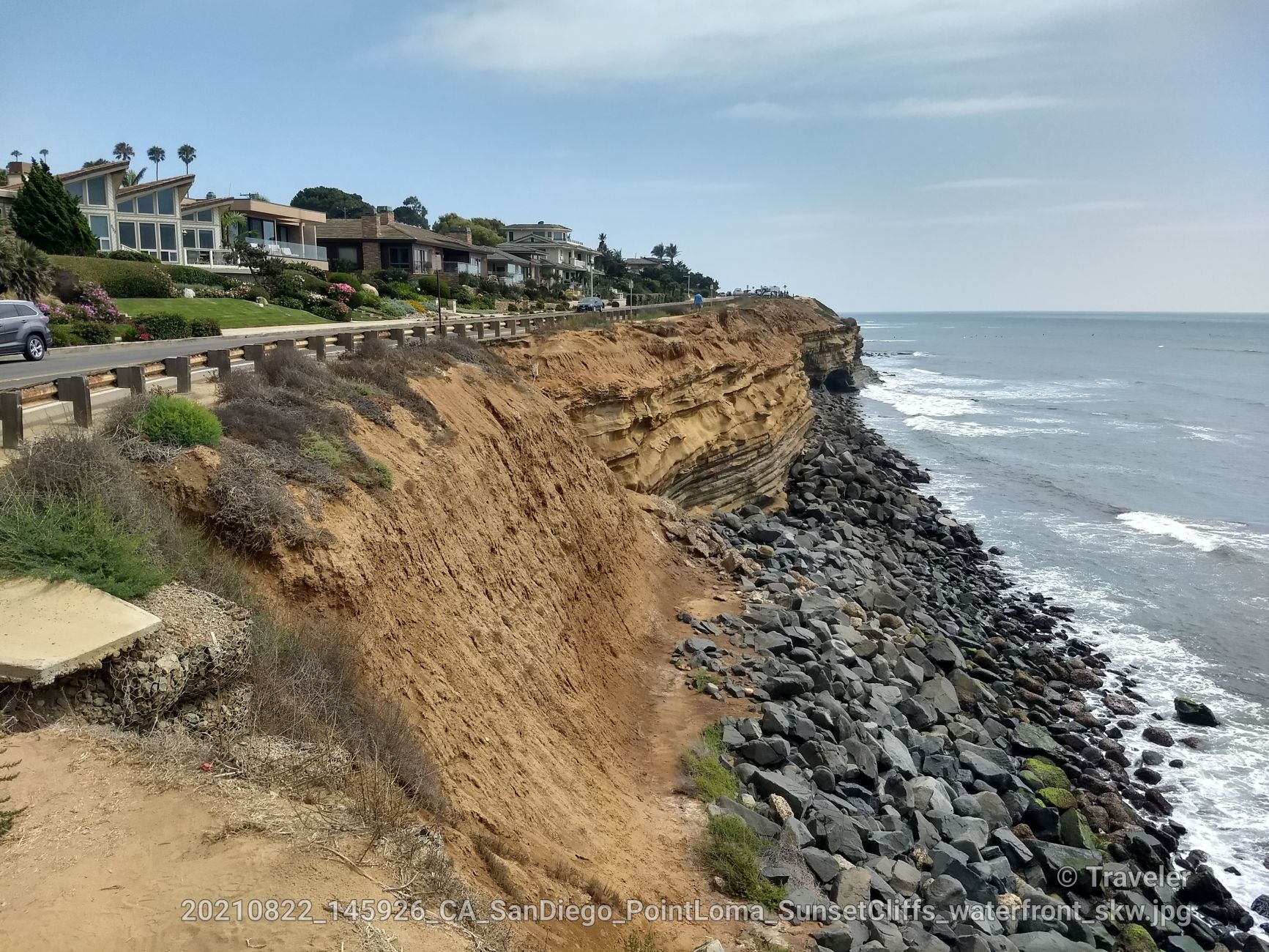 Coastal road alongside steep, layered cliffs dropping to a rocky ocean shore. - Smugglers Cave Overlook – Old Point Loma Lighthouse loop from Gaslamp Quarter
