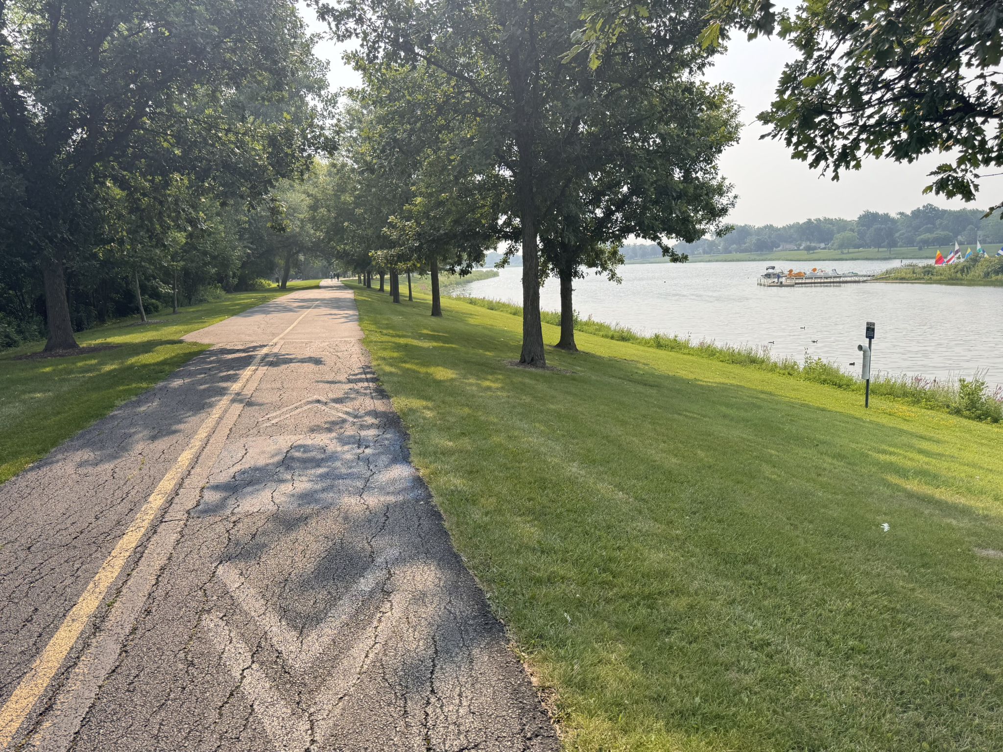 Paved path next to a river, lined with trees, under bright sunlight. - Baha'i Tample to Lake Arlington loop