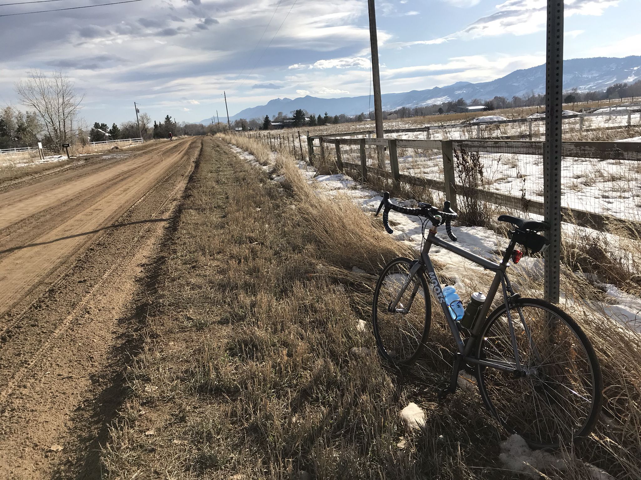 Bicycle parked on a dirt road next to a snowy field and distant mountains. - N. 39th/41st Street (Gravel) loop from Lefthand Trailhead