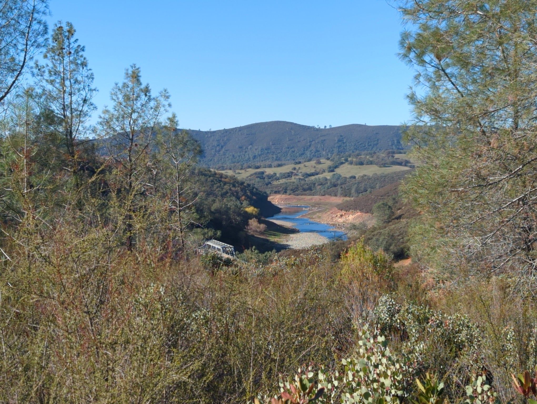 Bright view of a river winding through a valley with forested hills. - South Fork American River Trail