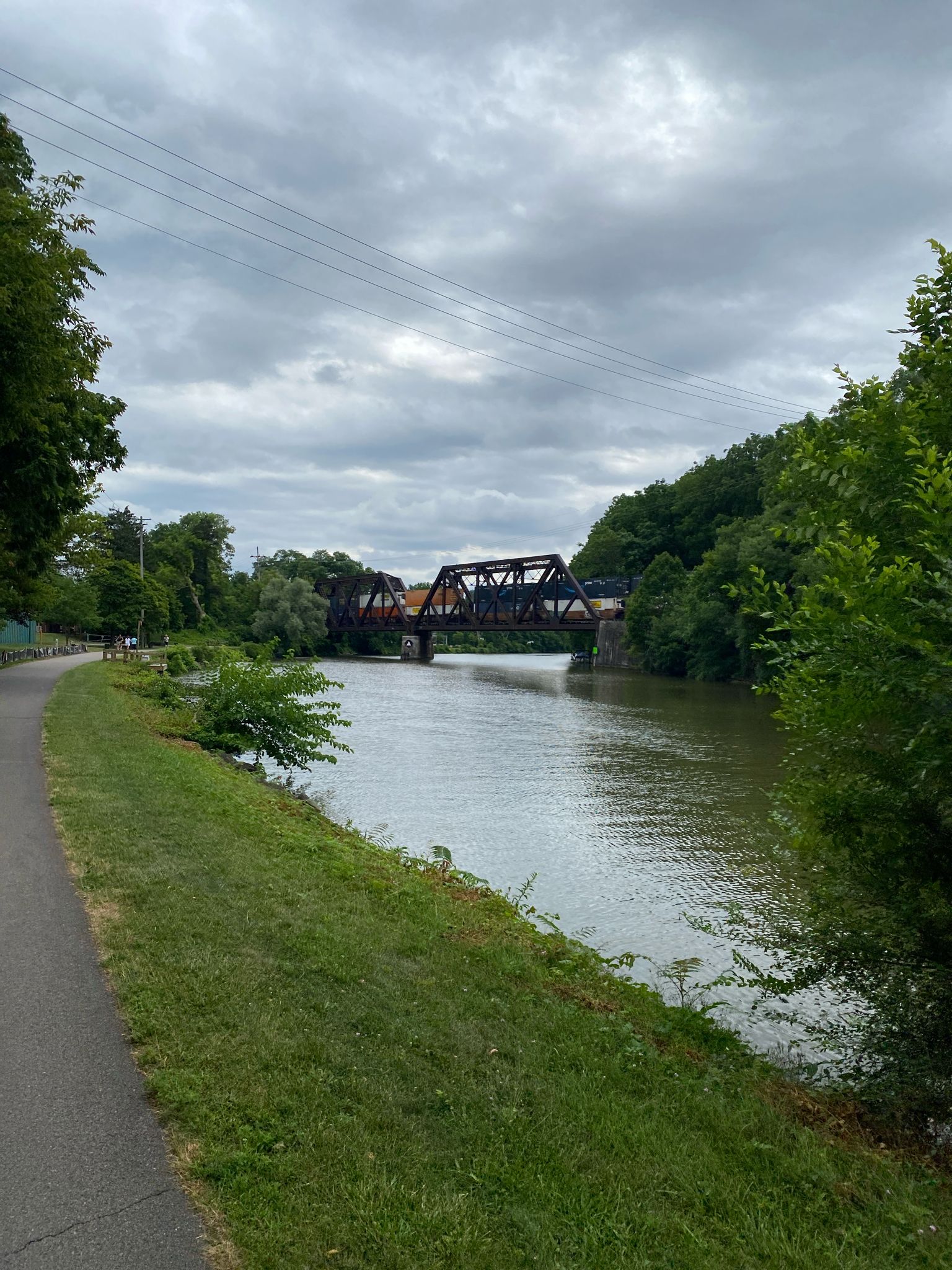 Paved path next to a river, with a large brown truss bridge in the distance. - Pittsford – Erie Canalway Trail loop from Village of Pittsford