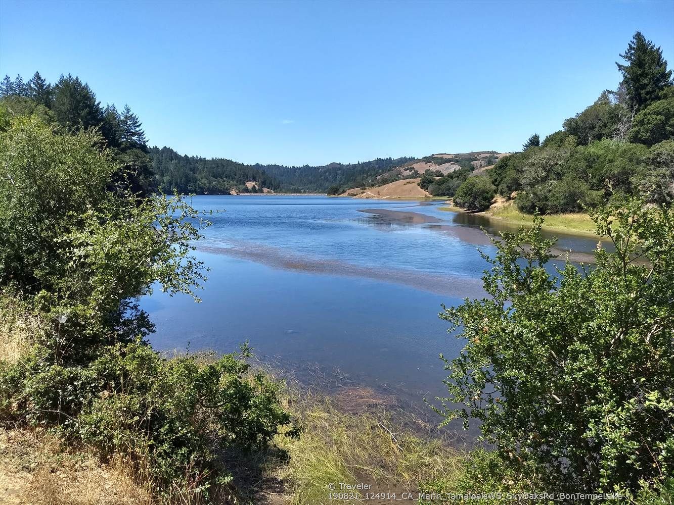Sunny view of a calm lake surrounded by green and dry hills. - Fern Creek and spring – Railroad Grade Fire Road loop from Mill Valley