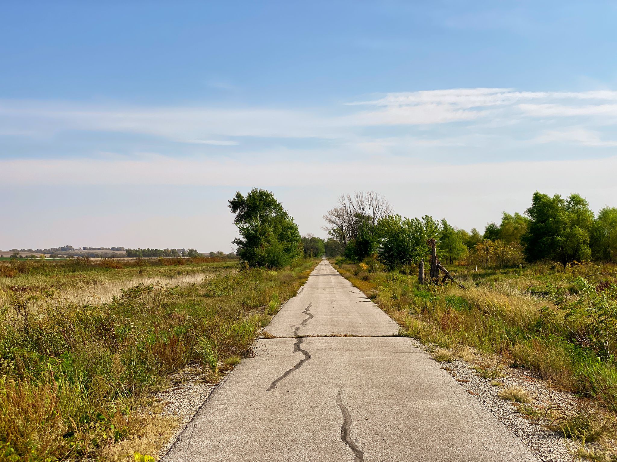 Long cracked paved path through dry grassy fields under a clear blue sky. - Summerset Trail