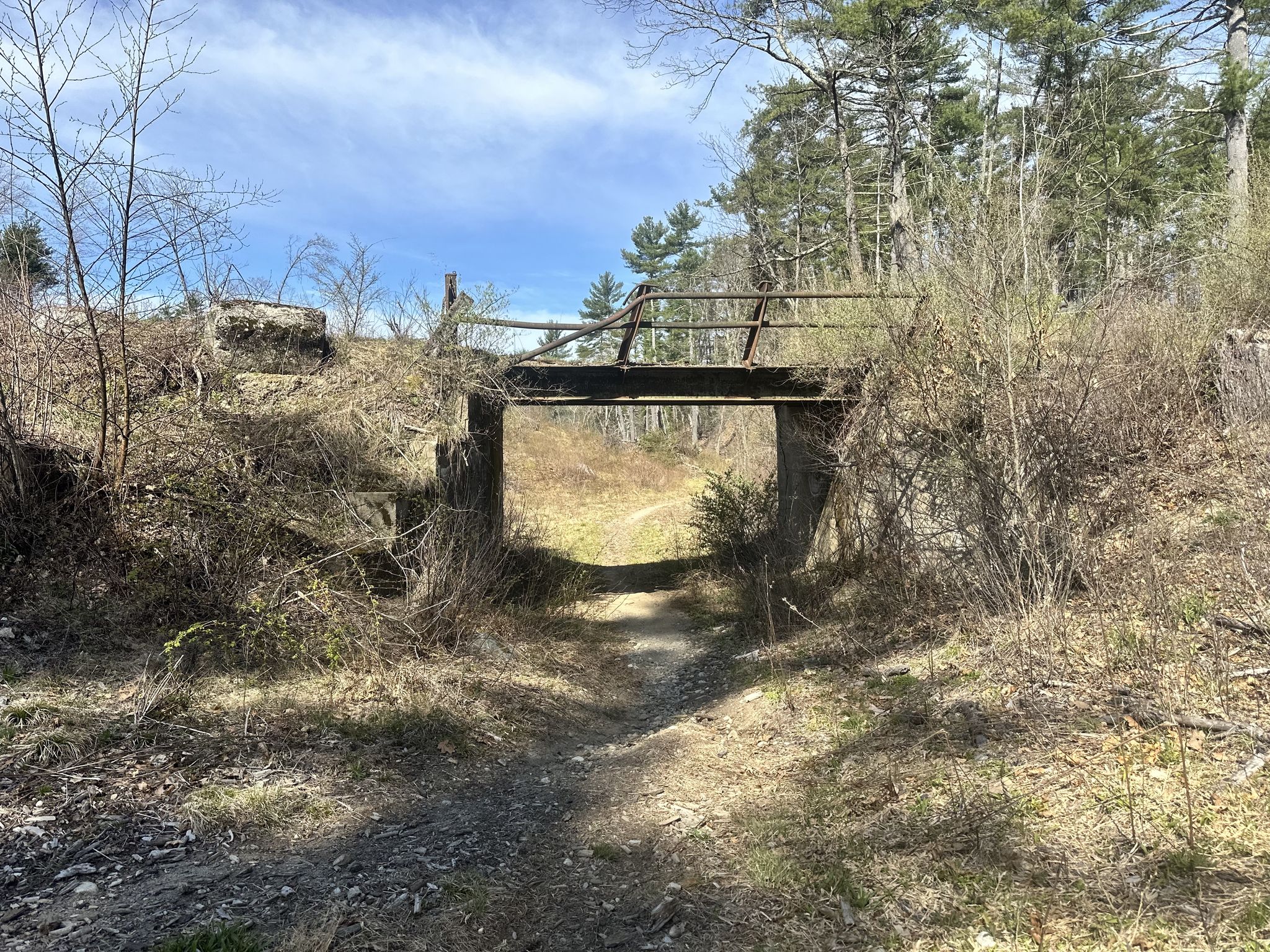 A rustic wooden bridge crosses over a dirt path in a sunny, wooded area. - Bear Hill loop from Millstone Hill Satellite Tracking Radar