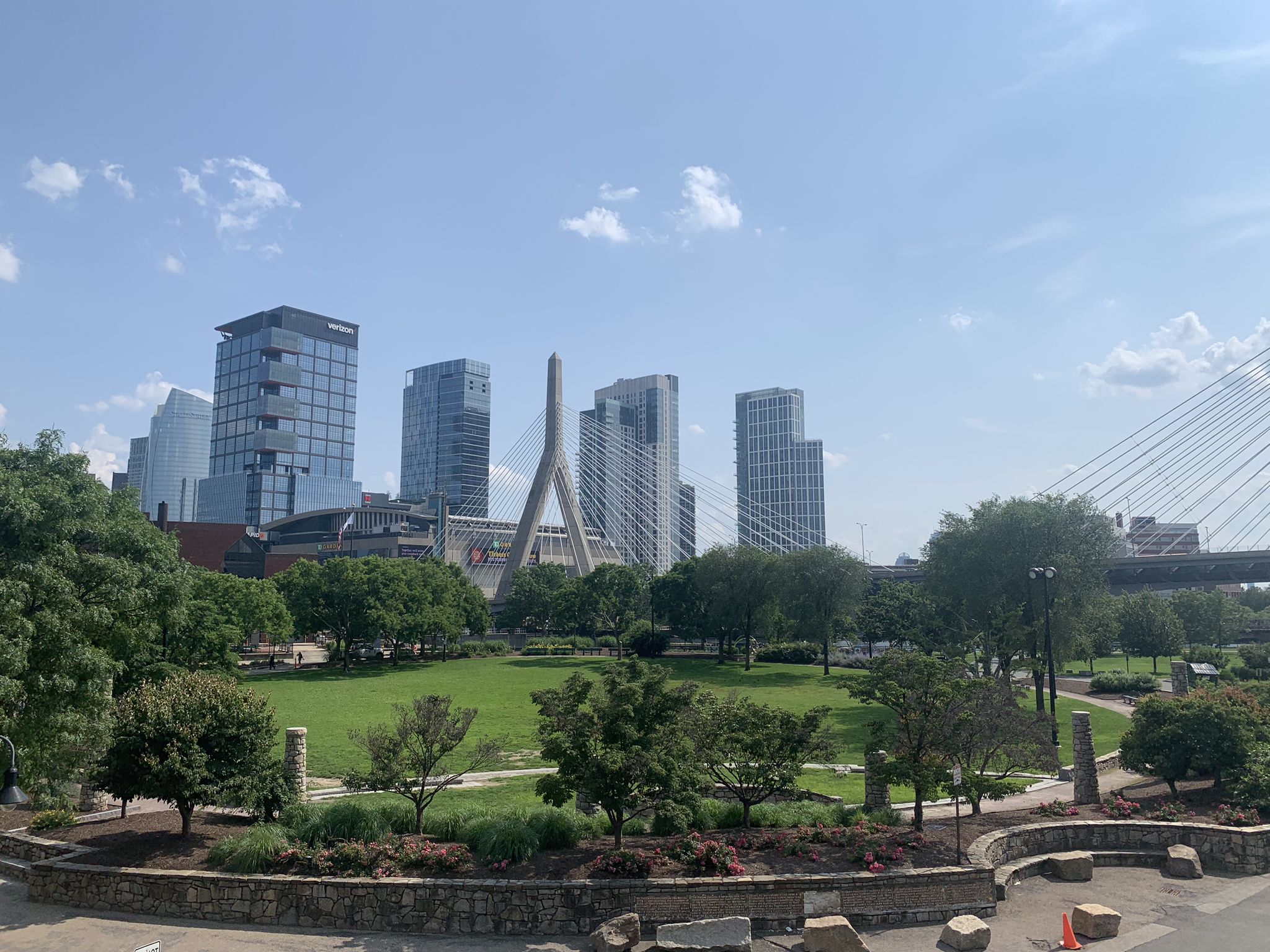City skyline with modern buildings, a bridge, and a green park. - Mass Central Rail Trail