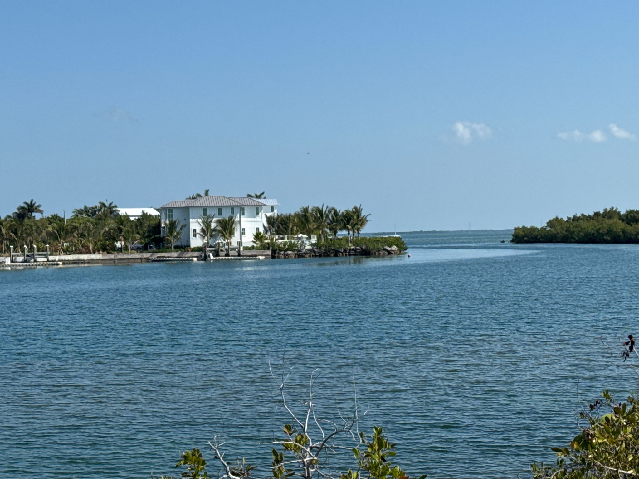 A large white house by a clear blue waterway with green islands. - Boyd's Campground loop from Stock Island