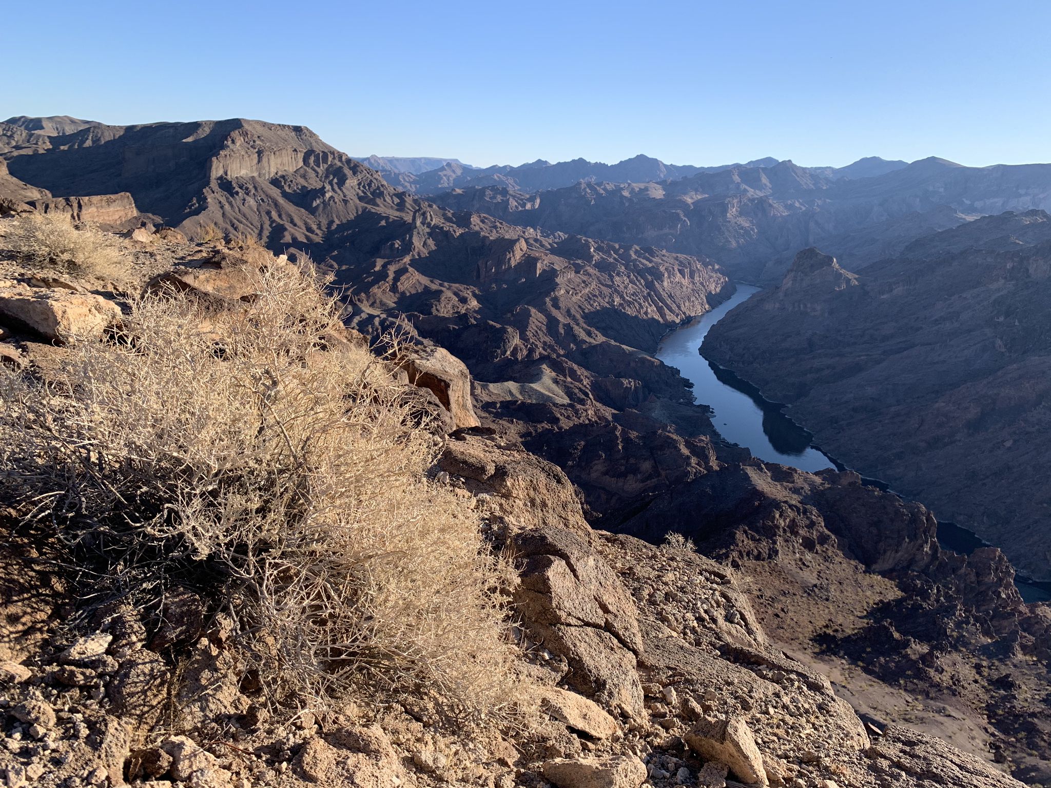 A wide desert canyon with a winding river, seen from a rocky overlook. - Liberty Bell Arch Trail