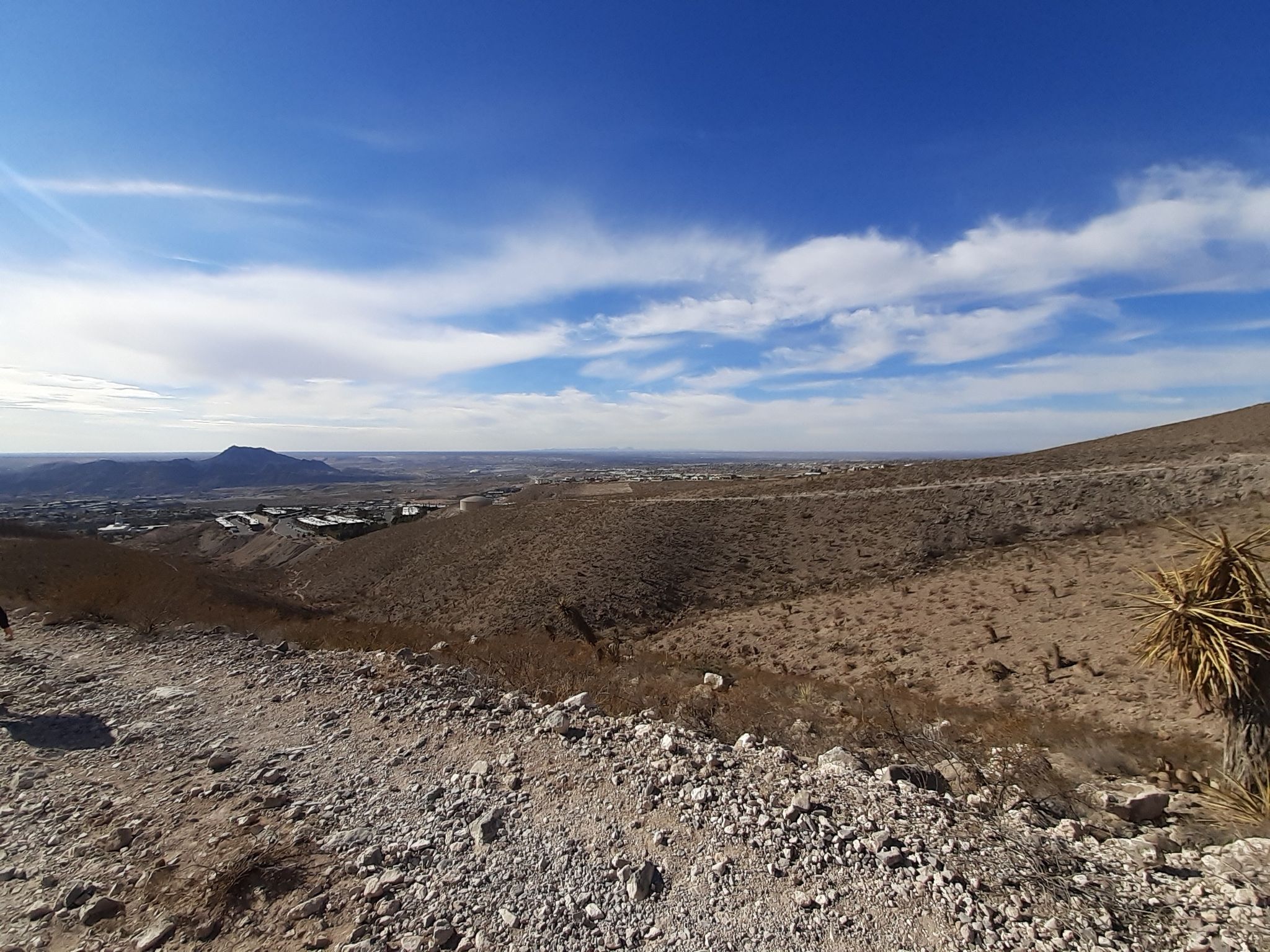 Vast desert landscape with distant city under a bright, cloudy sky. - Thousand Steps Trail