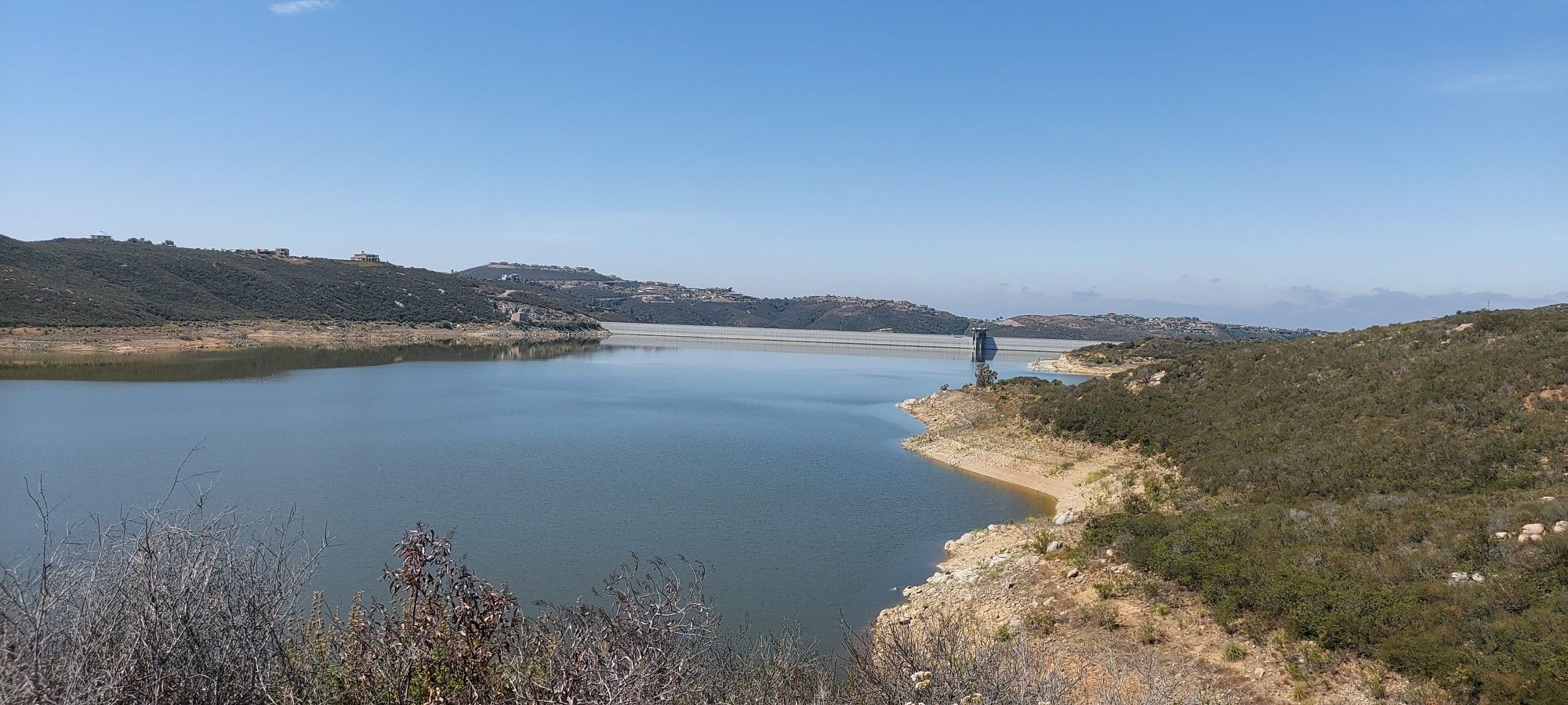 Wide view of a large lake surrounded by dry, green hills under a clear sky. - Lake Hodges Overlook Loop Trail