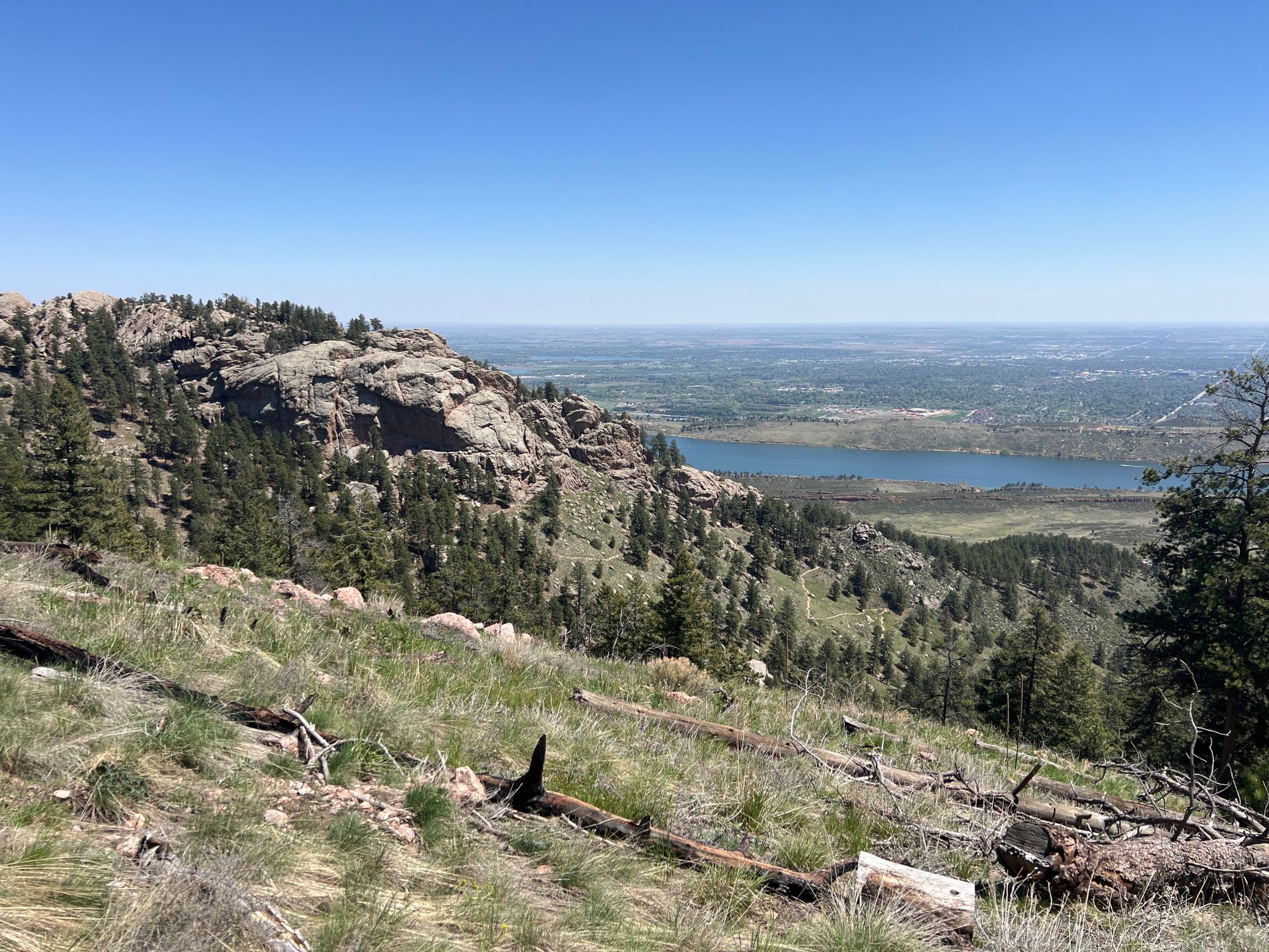 Rocky mountain landscape with pine trees overlooking a lake and distant plains under clear sky. - Howard and Westridge Loop Trail