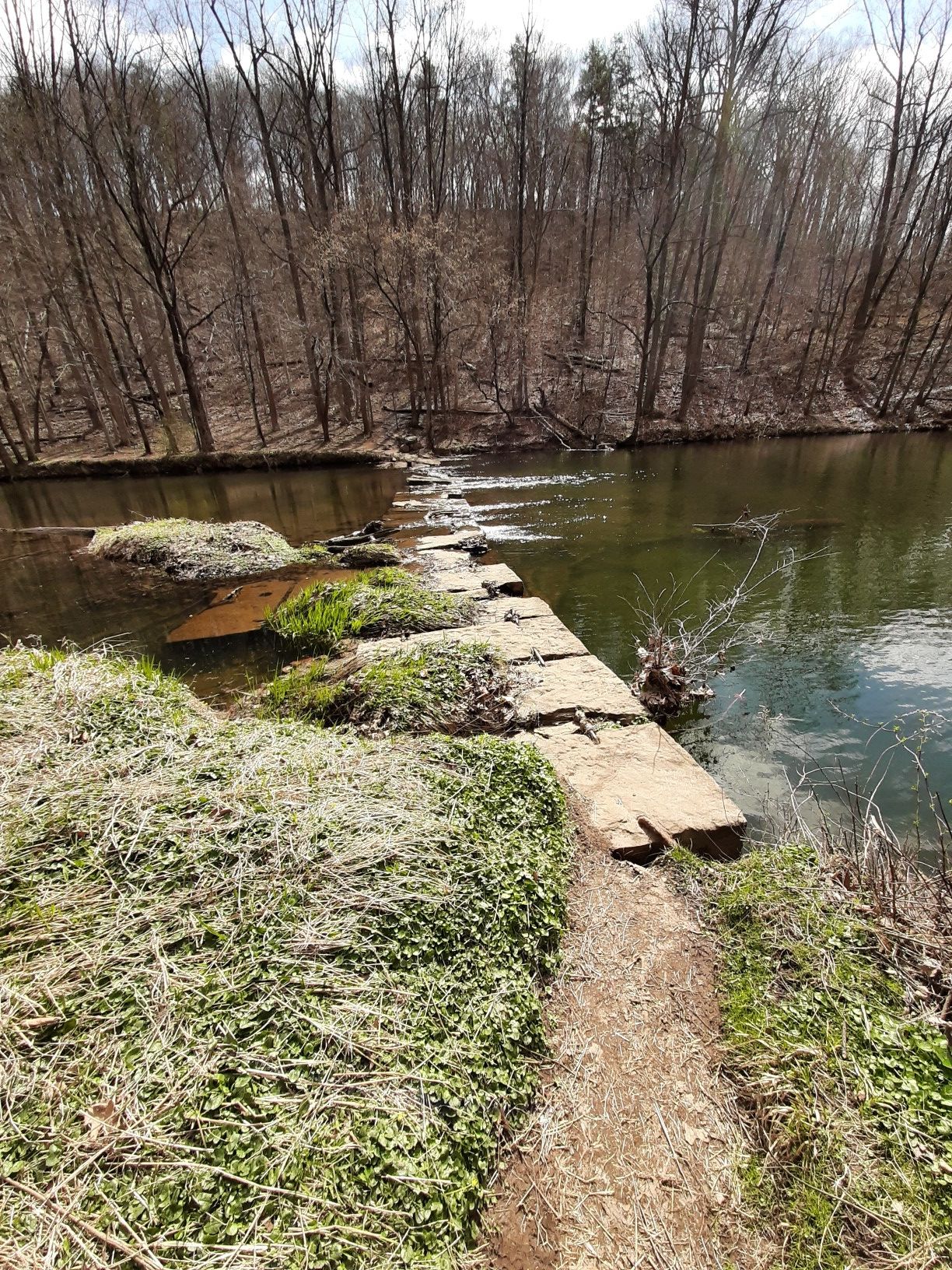 Concrete path extends into a river with bare trees under bright daylight. - Washington Valley Park – Washington Valley Park West loop from Martinsville