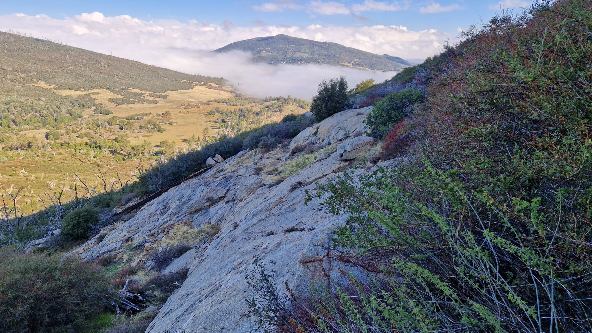 Mountain slope with rocky outcrops and green bushes, overlooking a foggy valley. - Stonewall Peak – Stonewall Peak loop from Paso Picacho Campground