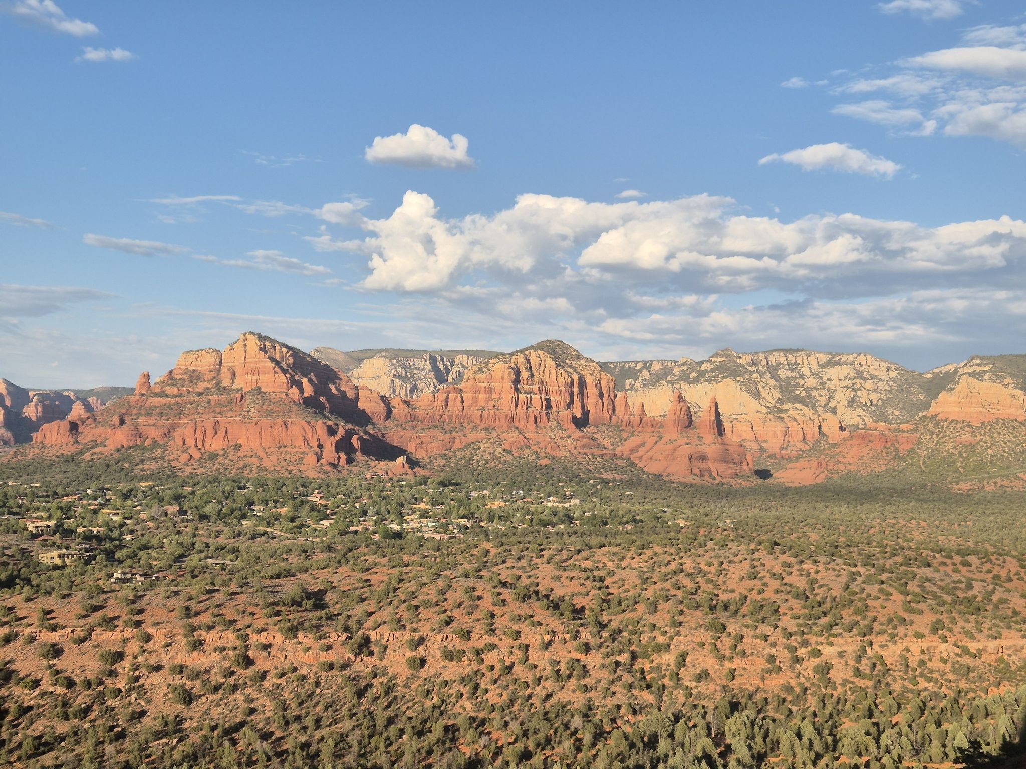 Expansive desert landscape with distant red rock mountains and scattered green vegetation. - Cathedral Rock Trail