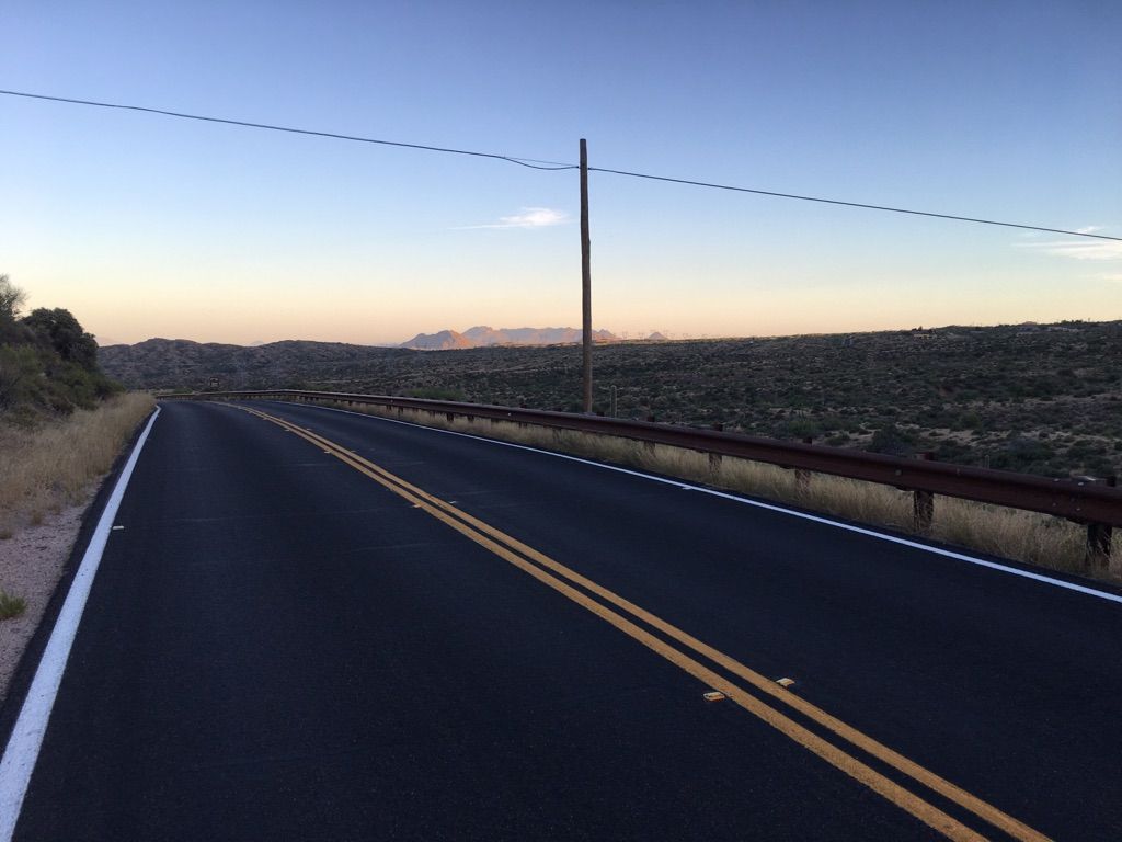Paved road curves through a desert landscape under a twilight sky. - North Flagstaff Powerline Road loop from Lone Mountain Ranch
