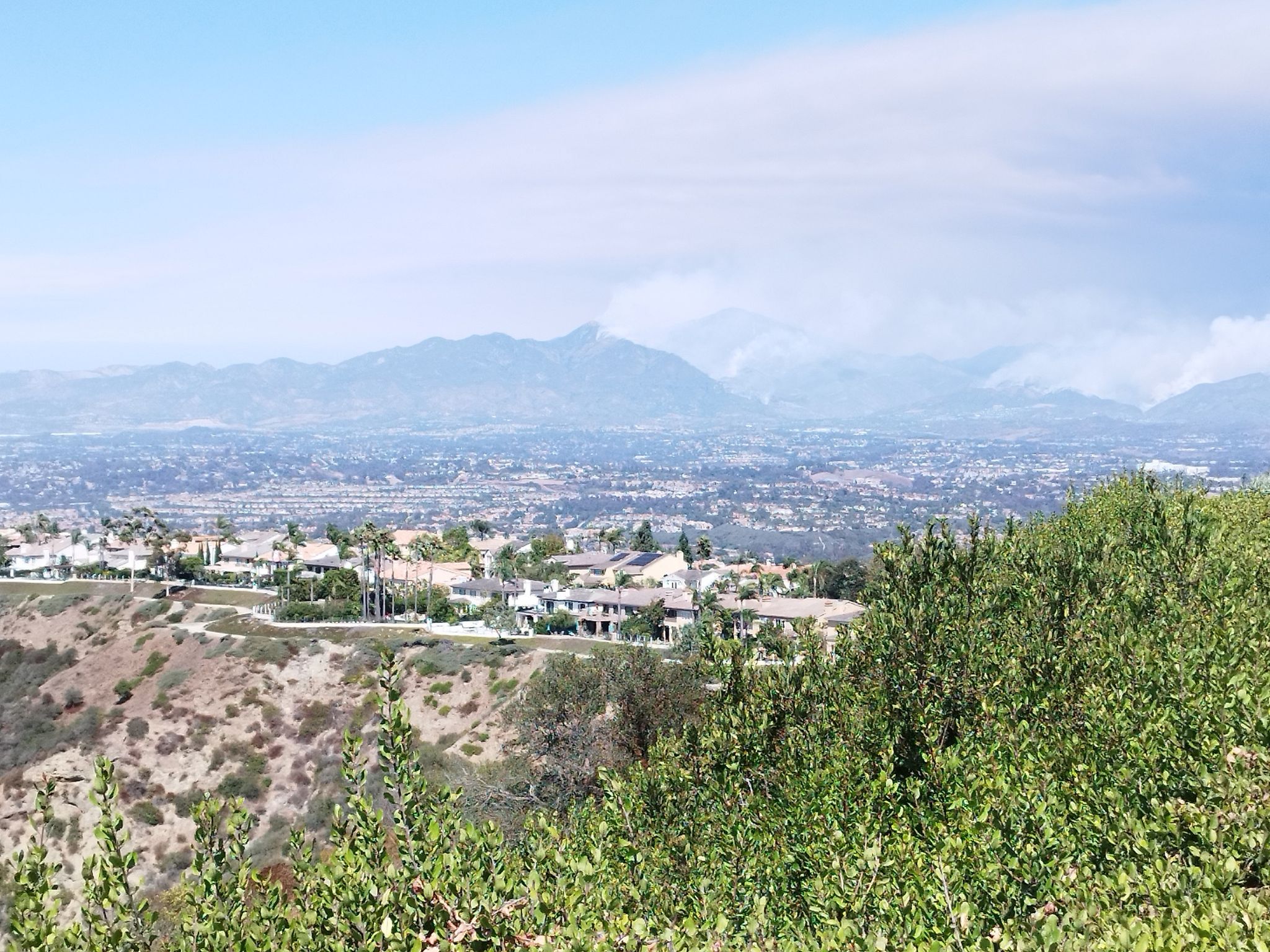 Overlook of a sprawling town and distant mountains on a clear, bright day. - Waterworks Flow Trail – Aliso Creek Trail loop from Trabuco Hills High School