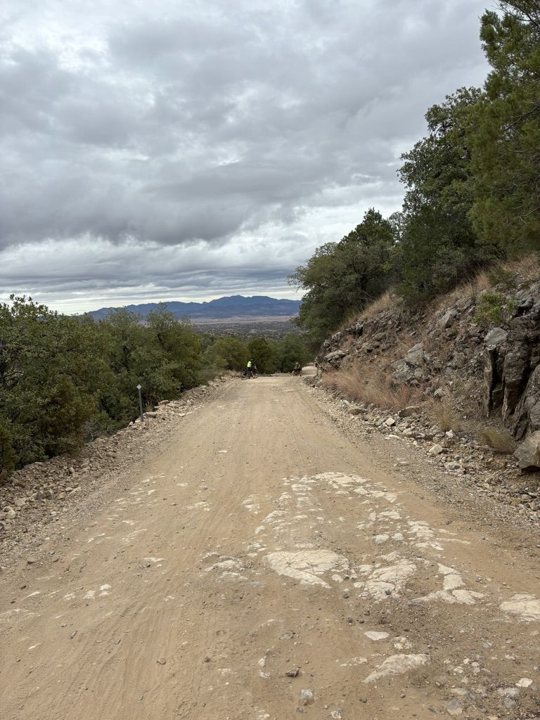 Dirt road ascending a hill with distant mountains under a cloudy sky. - Red Hill Loop