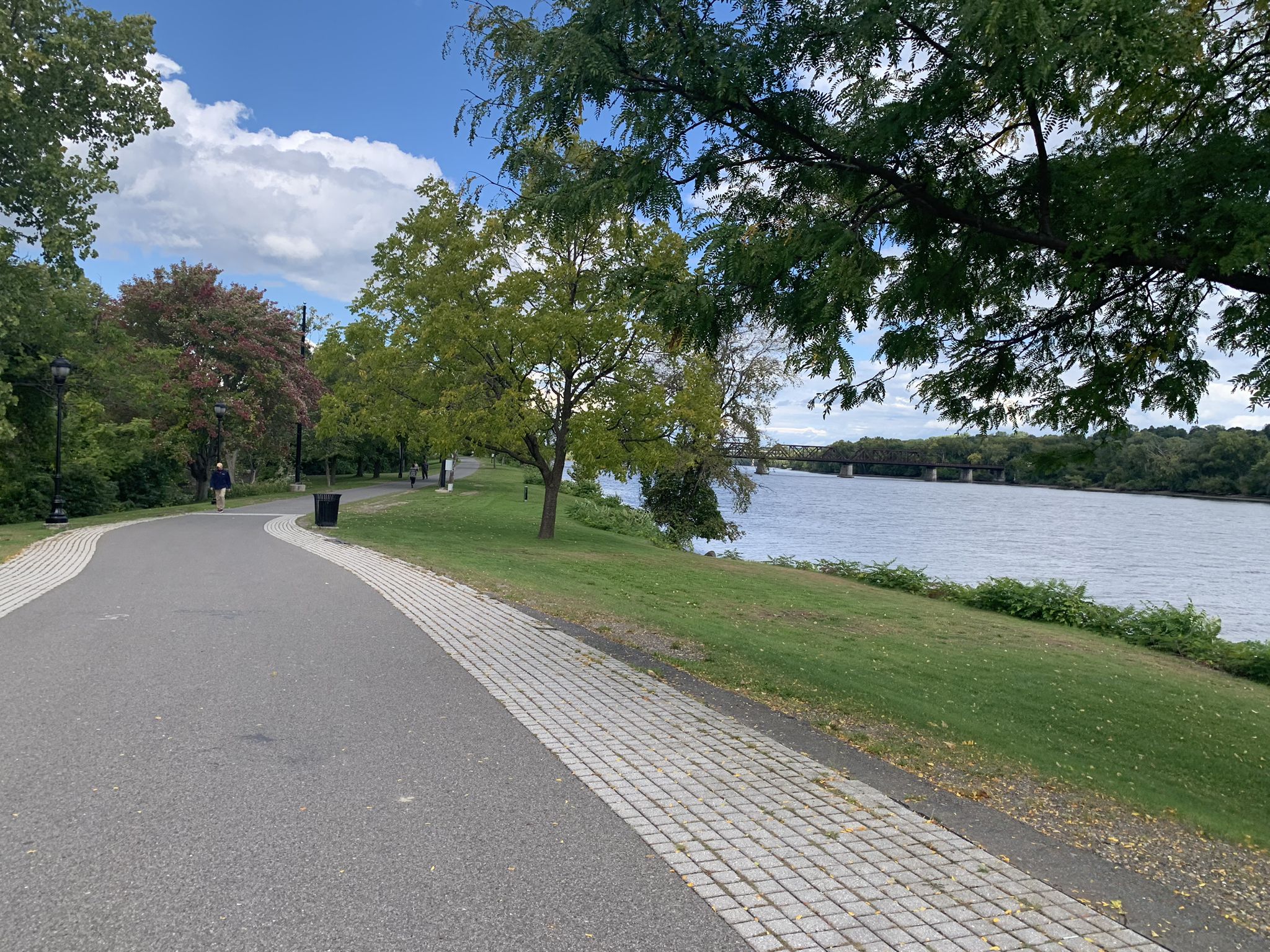 Paved path next to a wide river, lush green trees, bright day. - Mohawk-Hudson Trail and South End Connector Loop