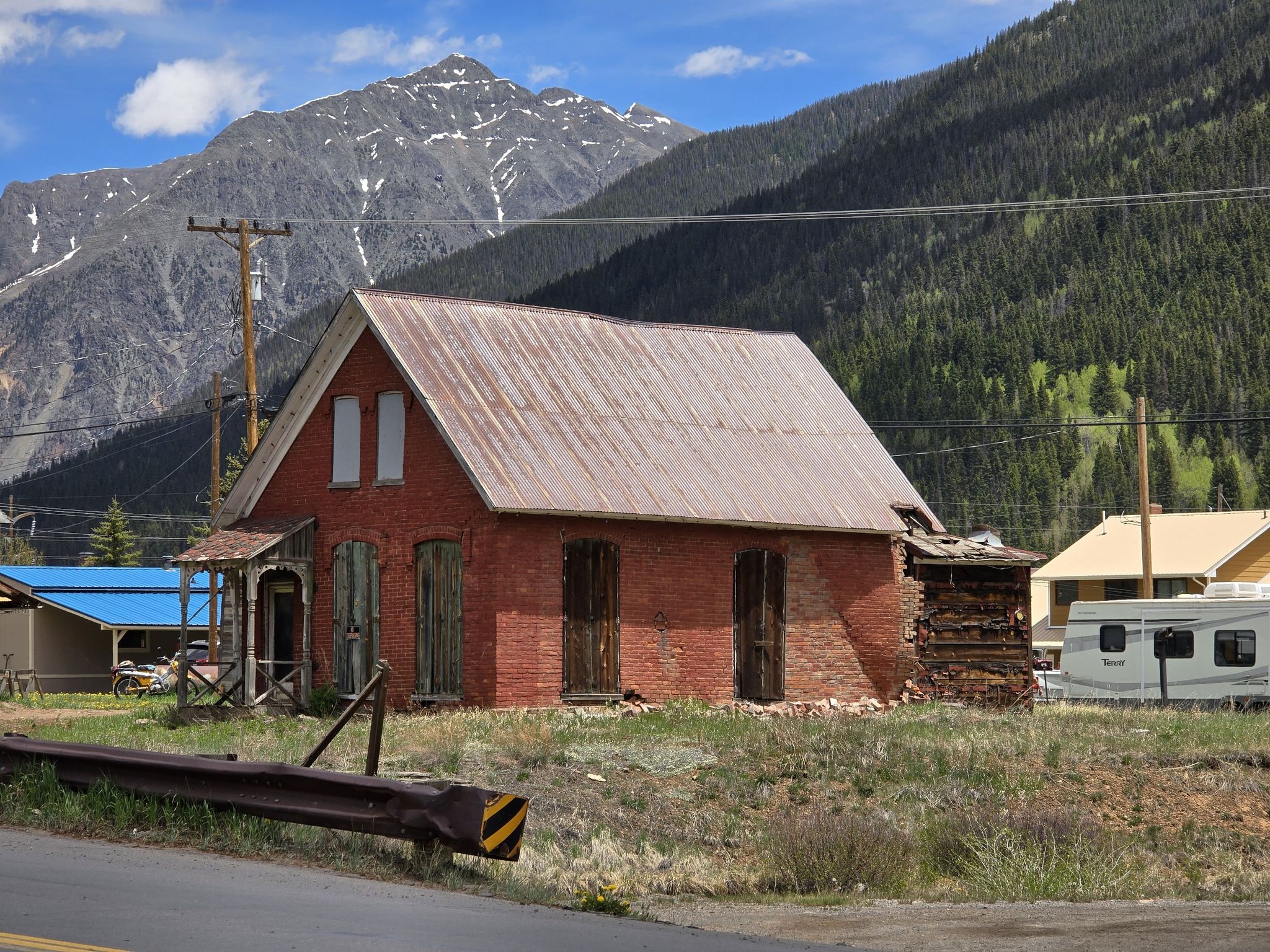 An old brick building stands in a mountain town under a bright sky. - Eureka loop