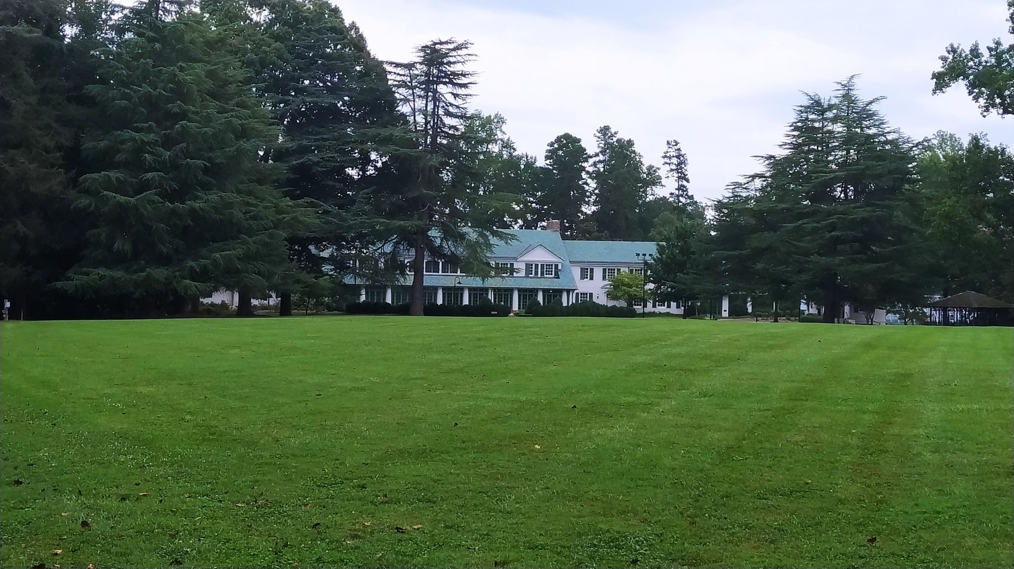 Large white building with green roof behind a vast green lawn, overcast day. - Reynolda Gardens loop from Winston-Salem