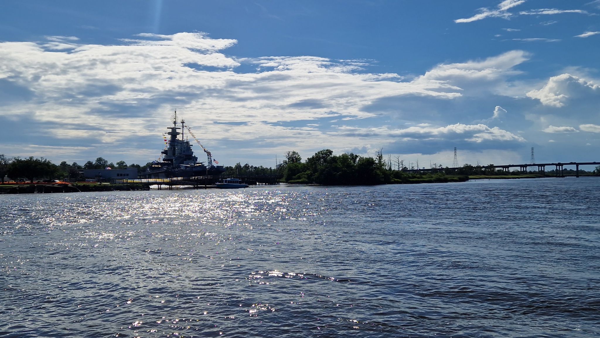 A large warship docked on a river under a partly cloudy sky. - Wilmington History Museum – Wilmington Riverwalk loop from Wilmington